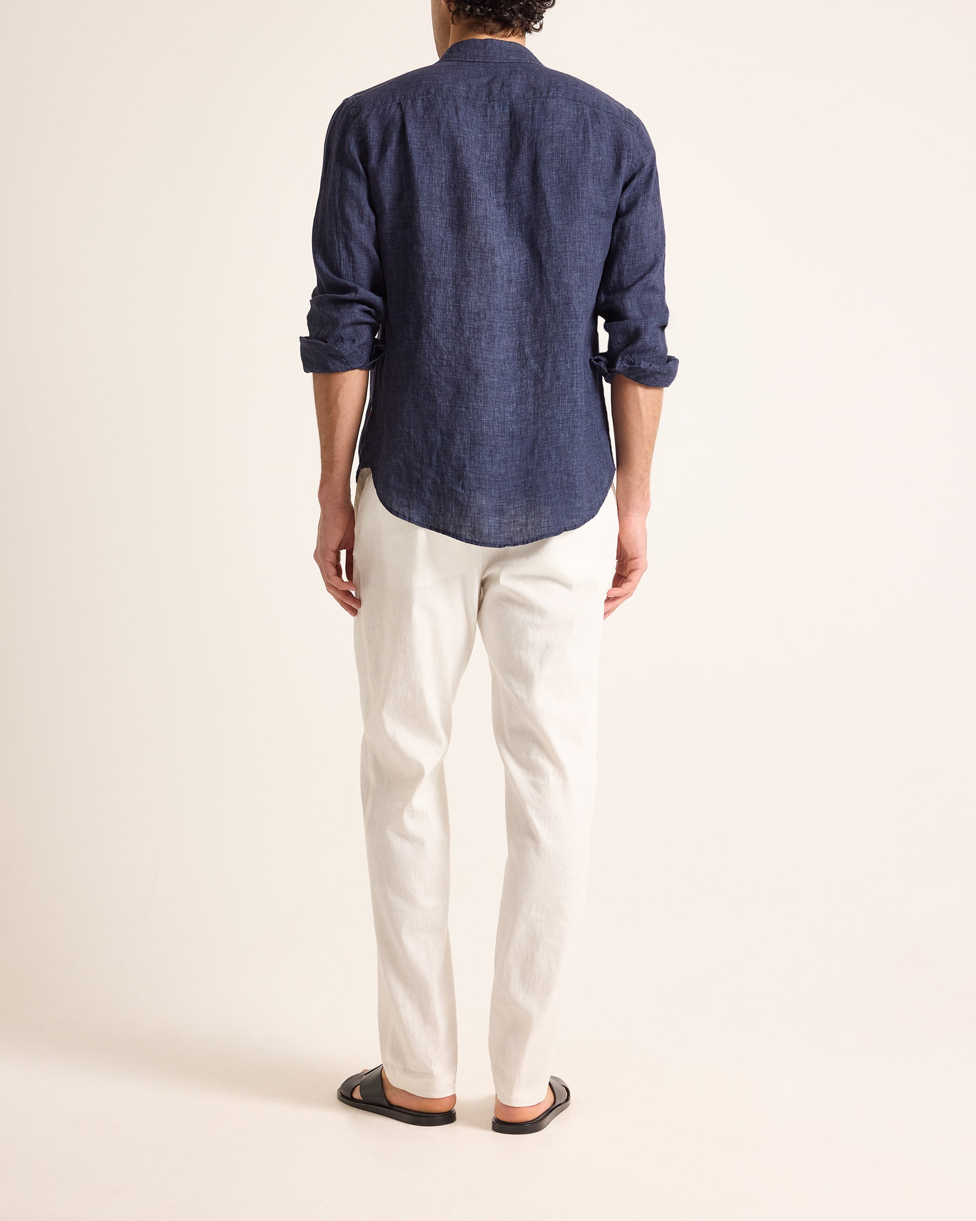 Person wearing a blue shirt and white pants on a plain background