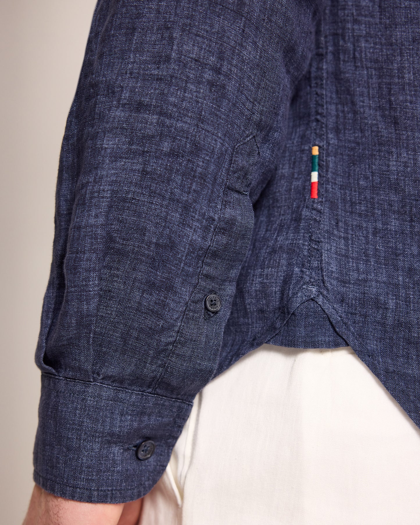 Close-up of a blue denim shirt with a brand logo on a neutral background