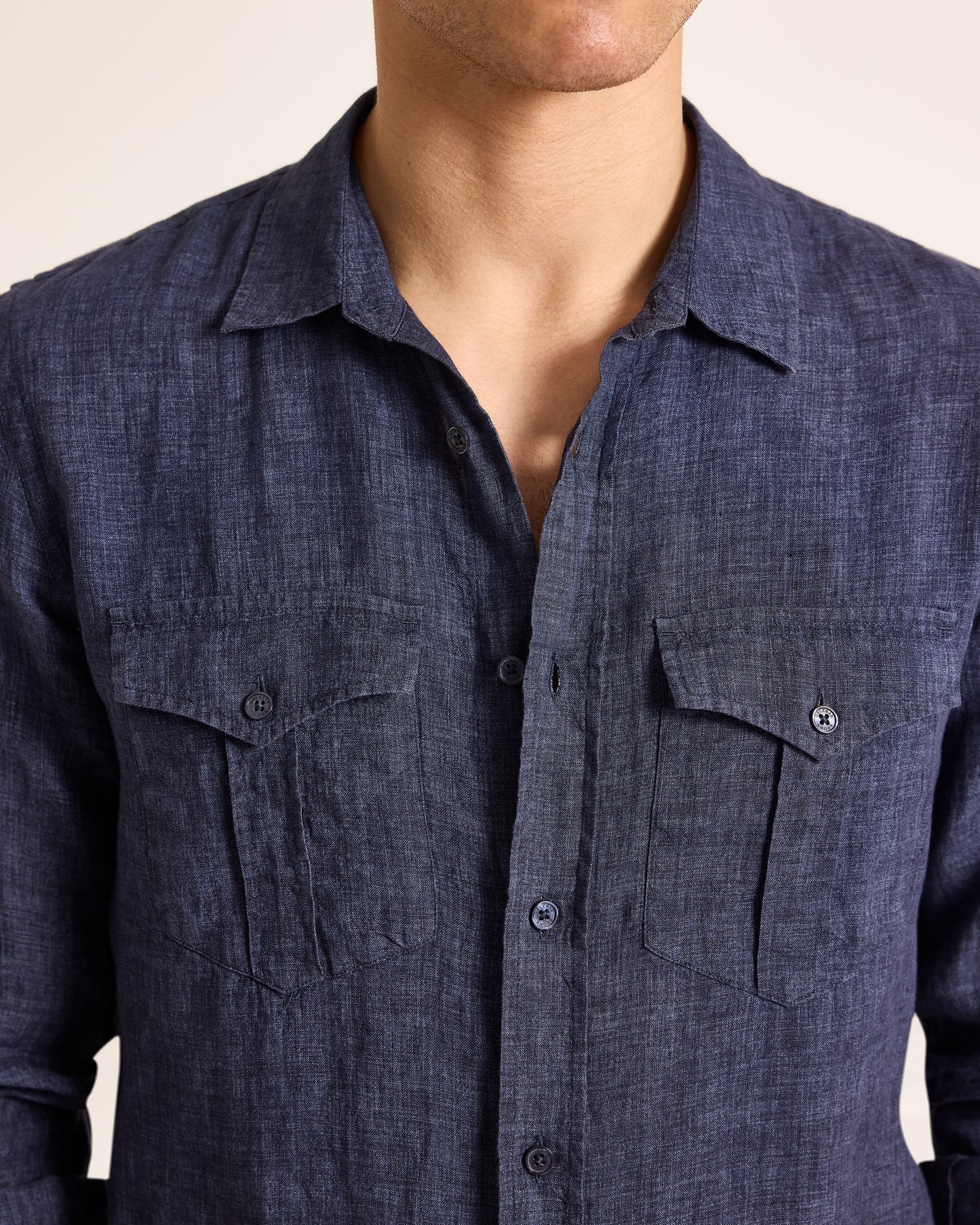 Navy blue button-up shirt worn by a person on a beige background