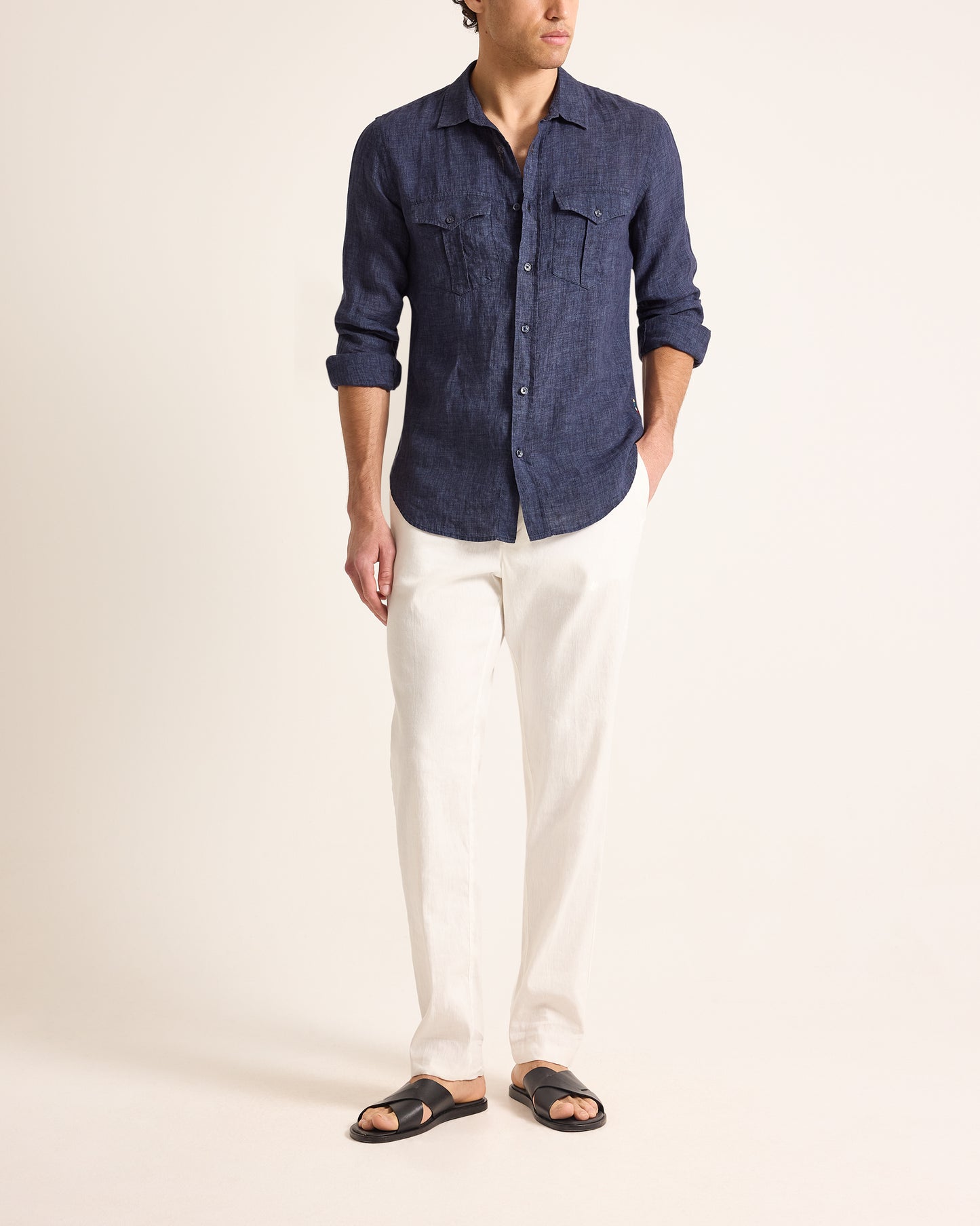 Person wearing a blue denim shirt and white pants on a plain background