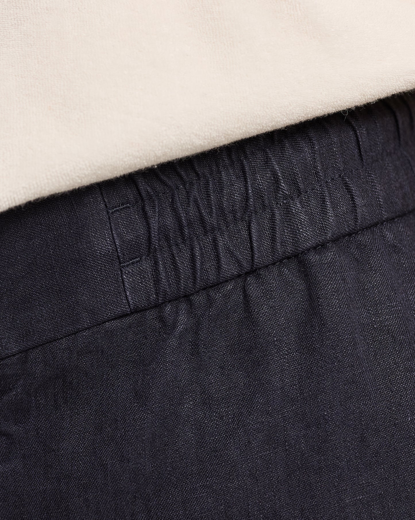Close-up of dark navy pants with a beige background