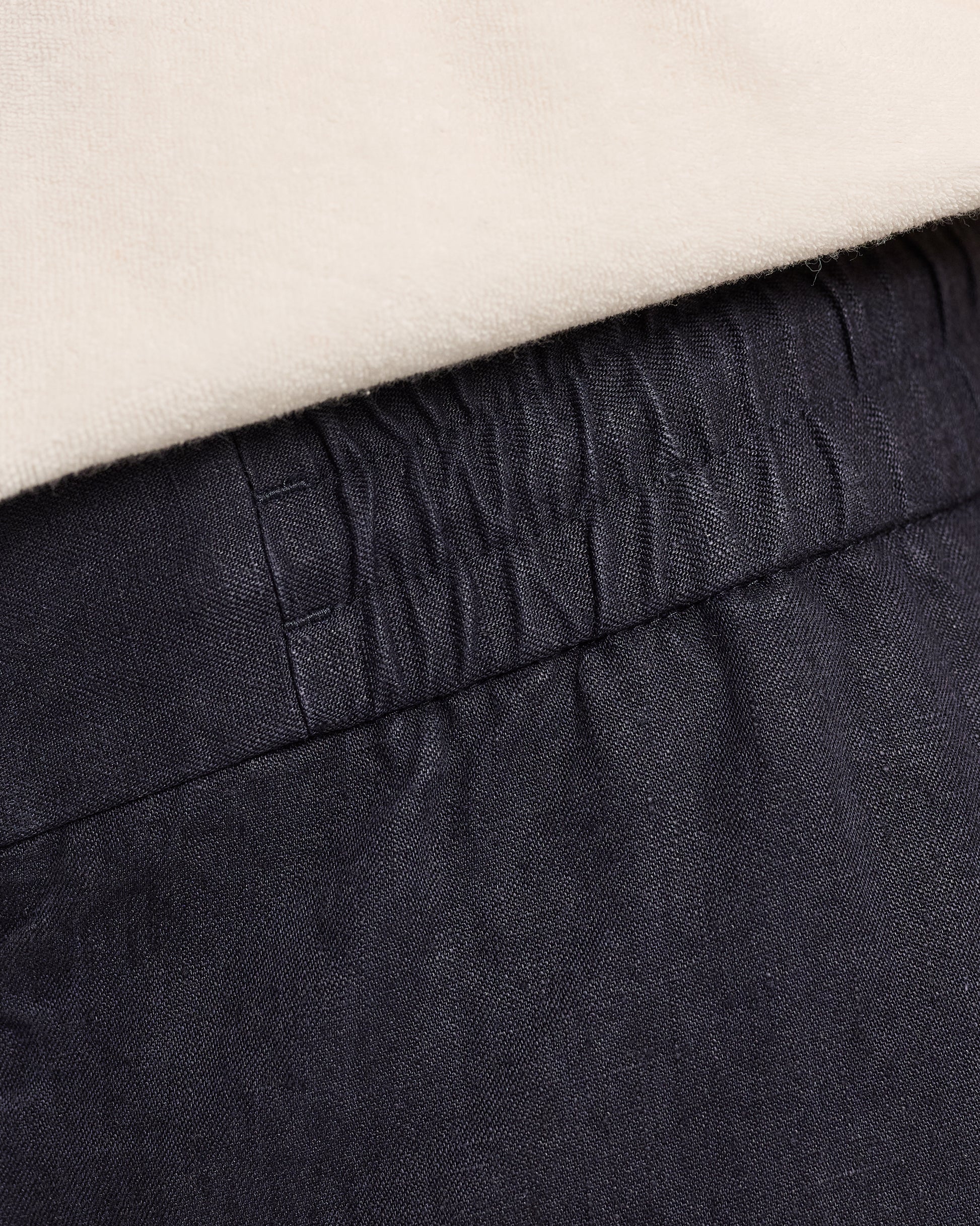 Close-up of dark navy pants with a beige background