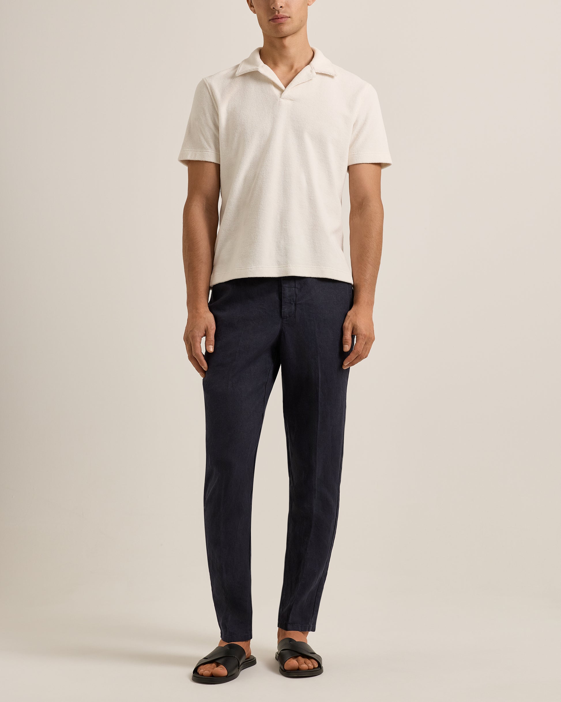 Person wearing a white polo shirt and navy pants on a plain background
