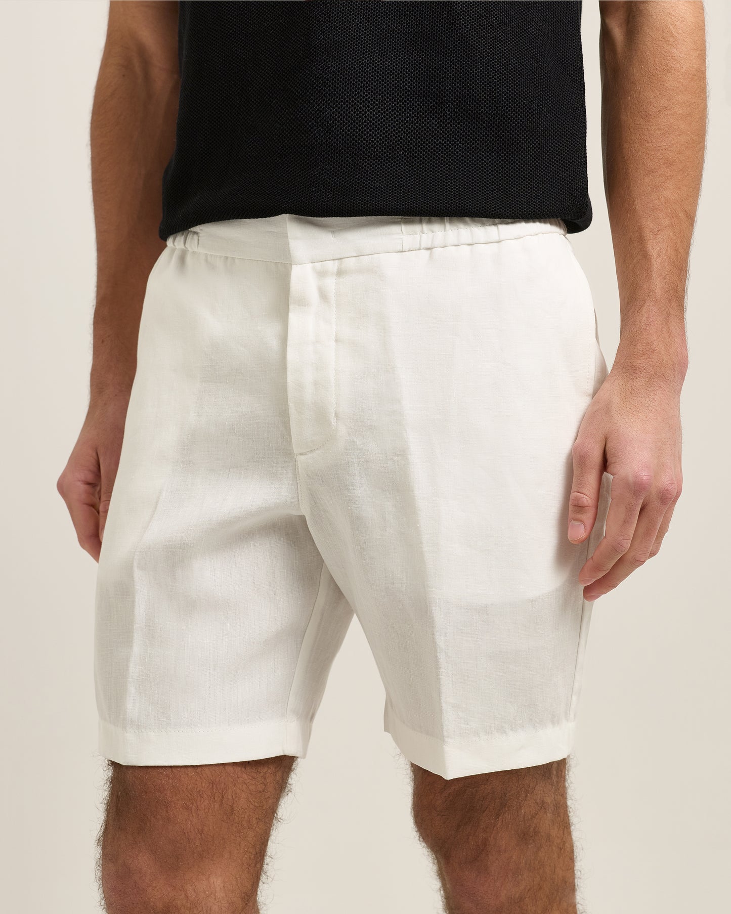 Person wearing white shorts and a black top on a plain background