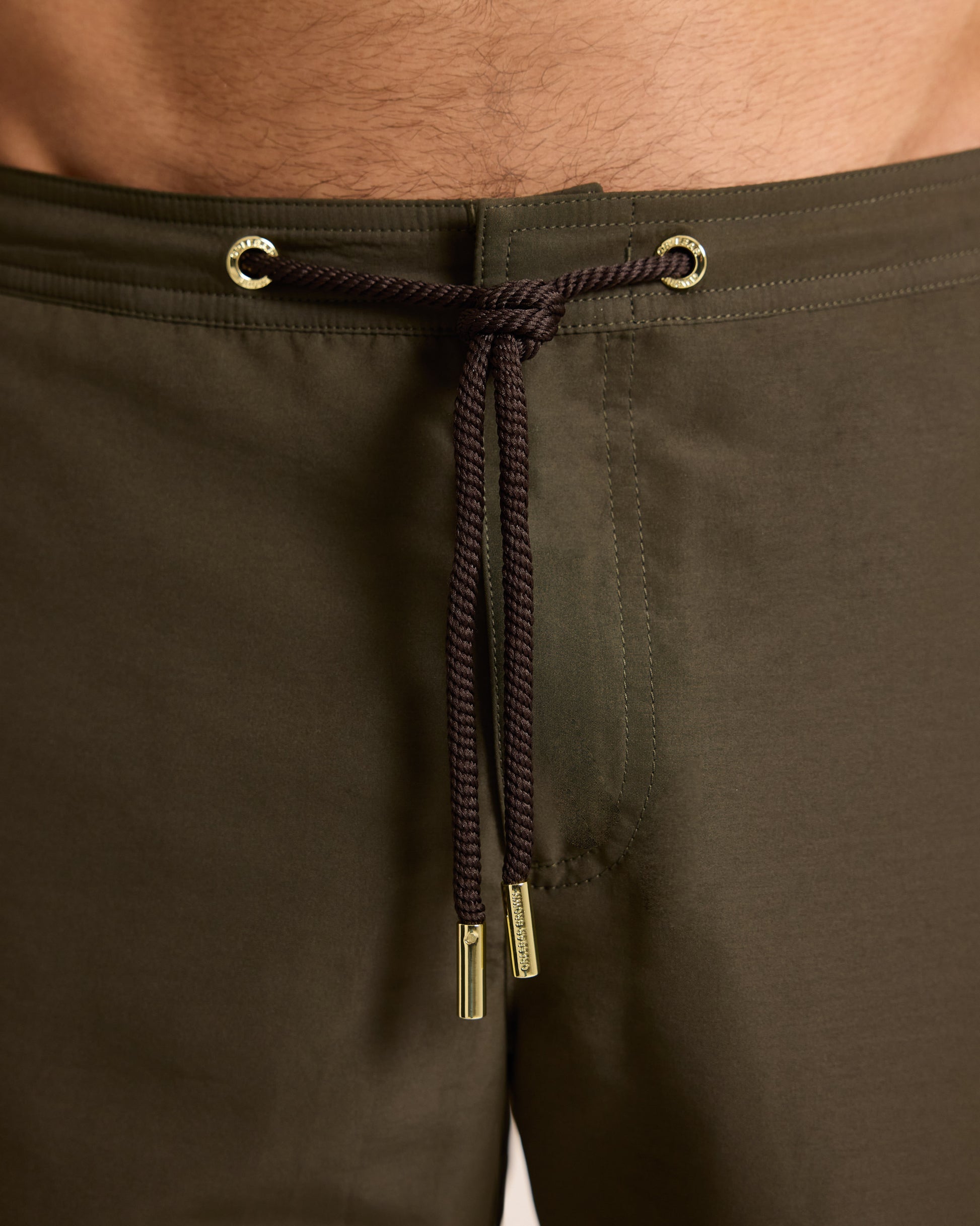 Brown pants with a drawstring and metal details on a neutral background