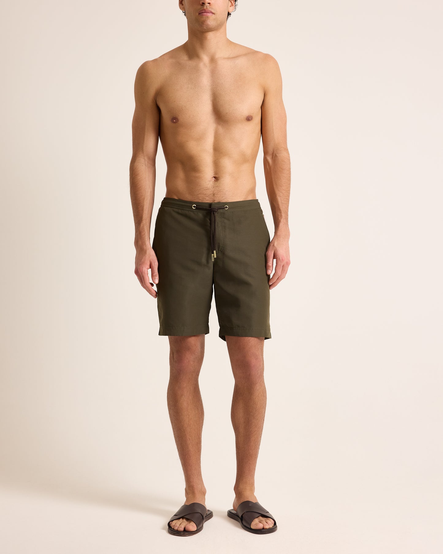 Man wearing olive green shorts on a beige background