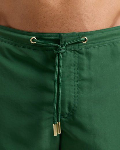 Close-up of green swim shorts with drawstring and metal grommets.