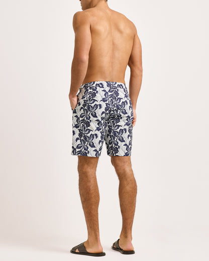 Man wearing navy floral swim shorts on a white background