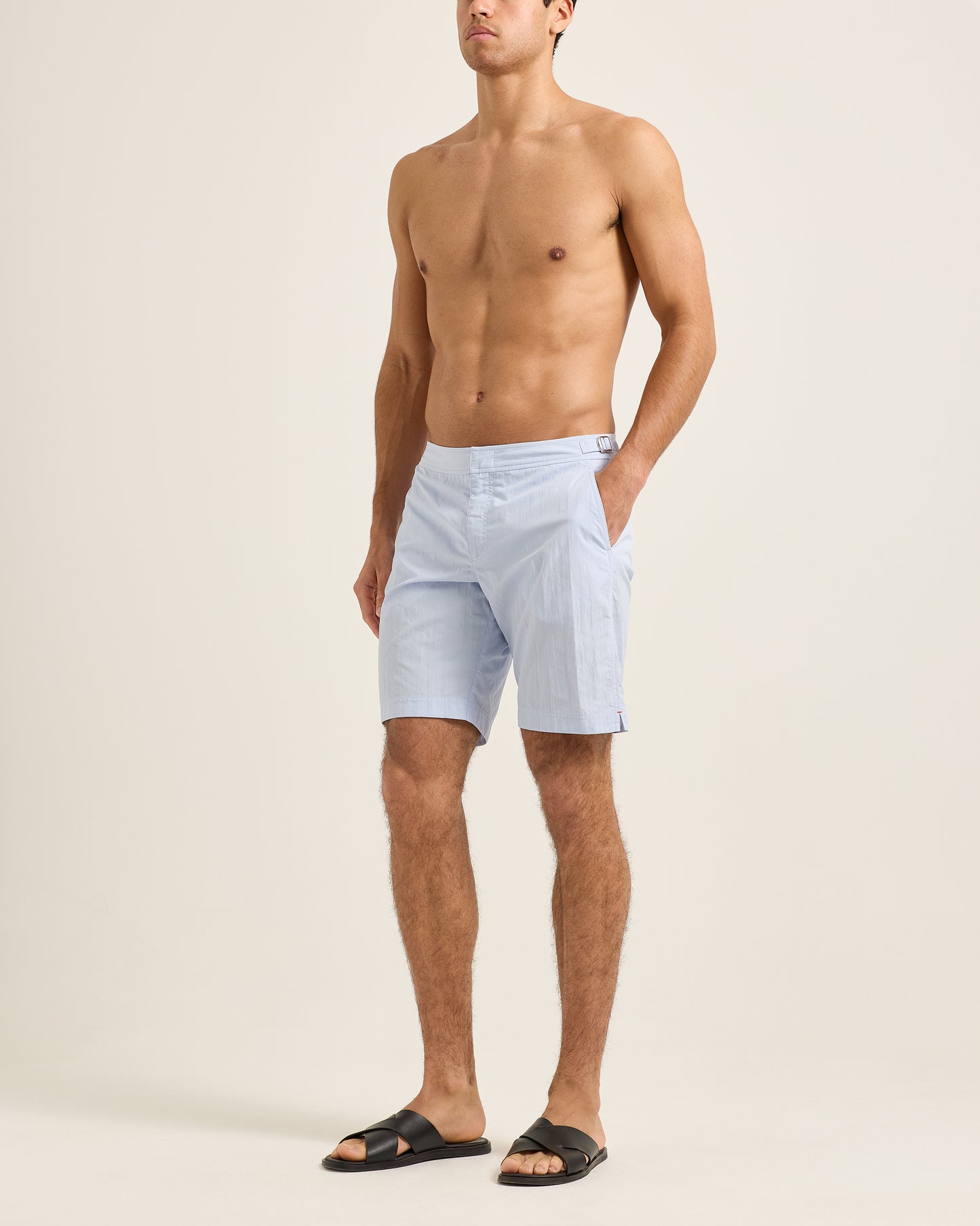 Man wearing light blue shorts on a beige background