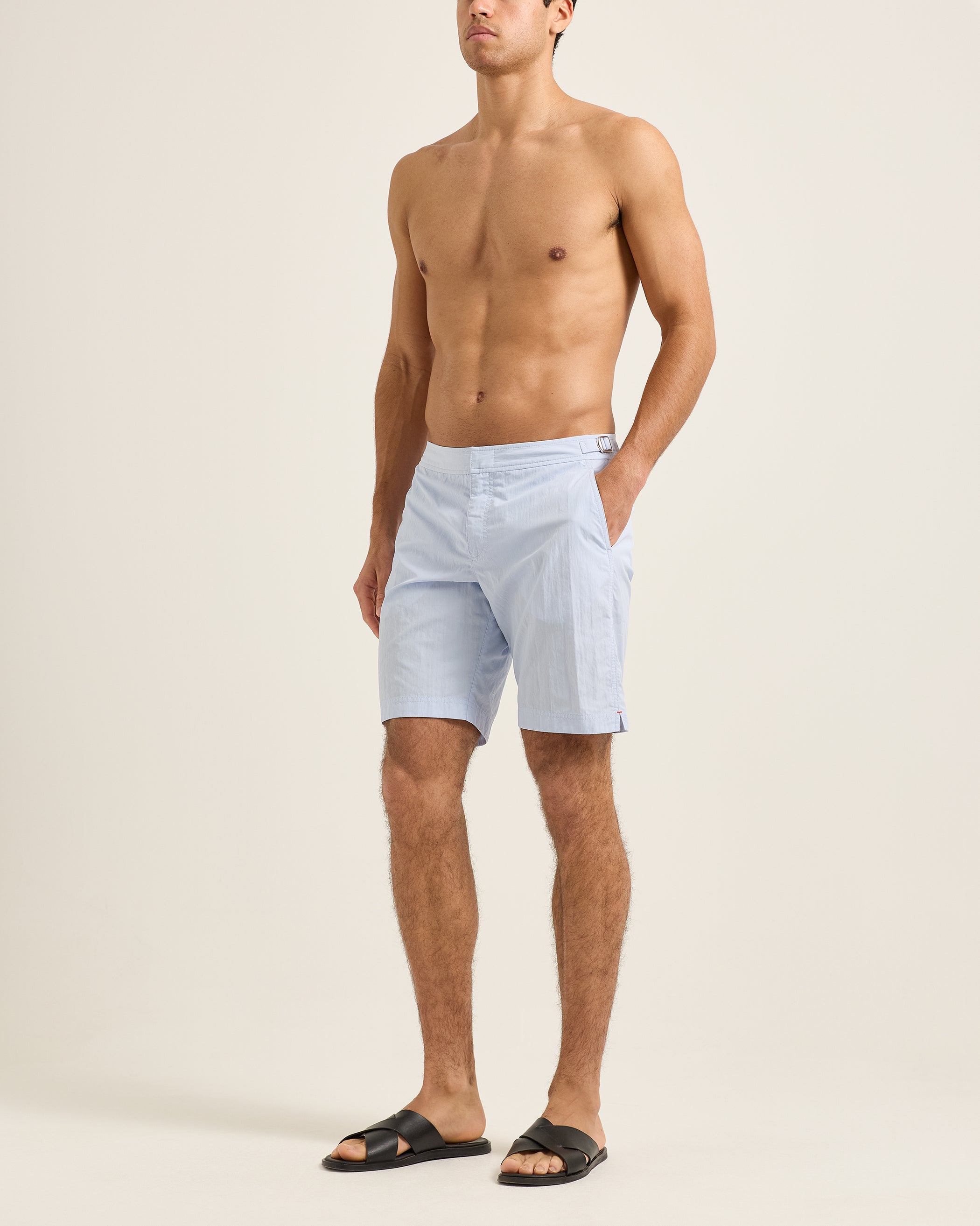 Man wearing light blue shorts on a beige background