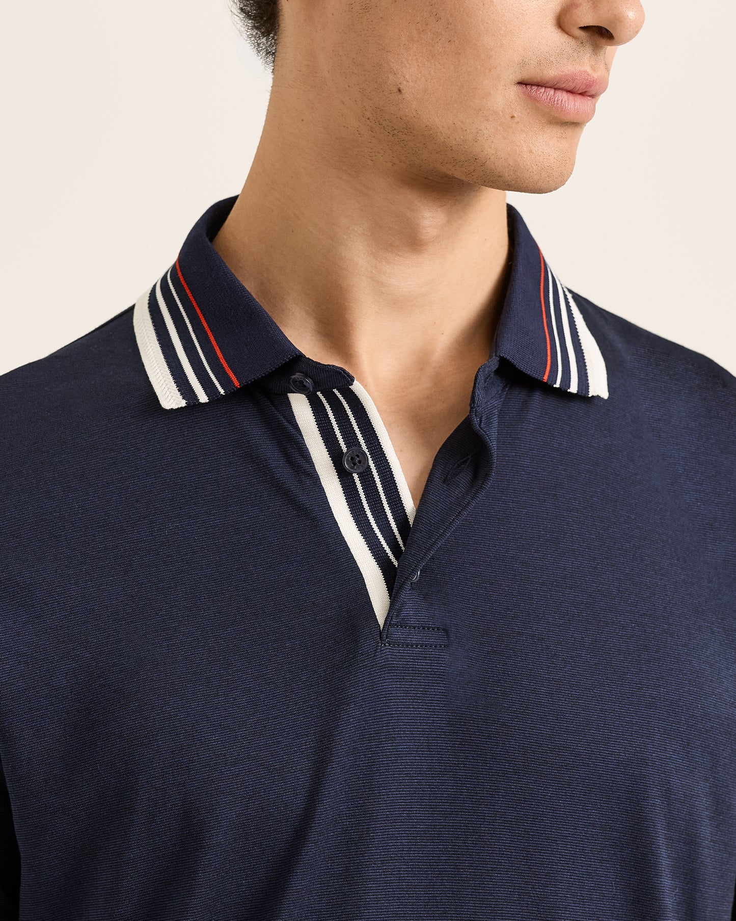 Navy polo shirt with striped collar detail on a neutral background