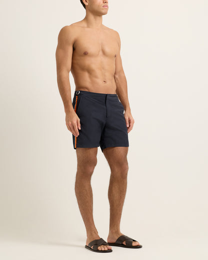Man wearing navy swim shorts on a beige background