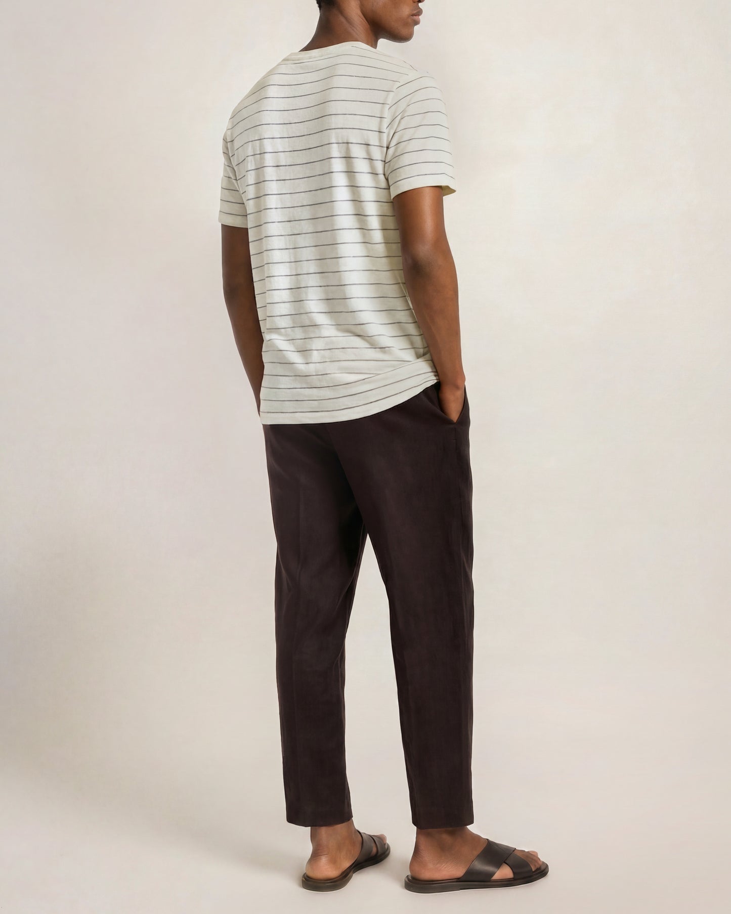 Man wearing a striped shirt and dark pants against a plain background