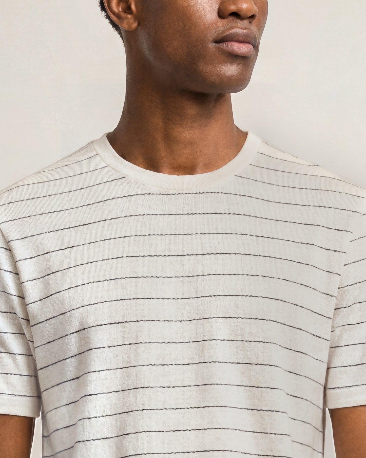 Person wearing a beige striped t-shirt against a neutral background