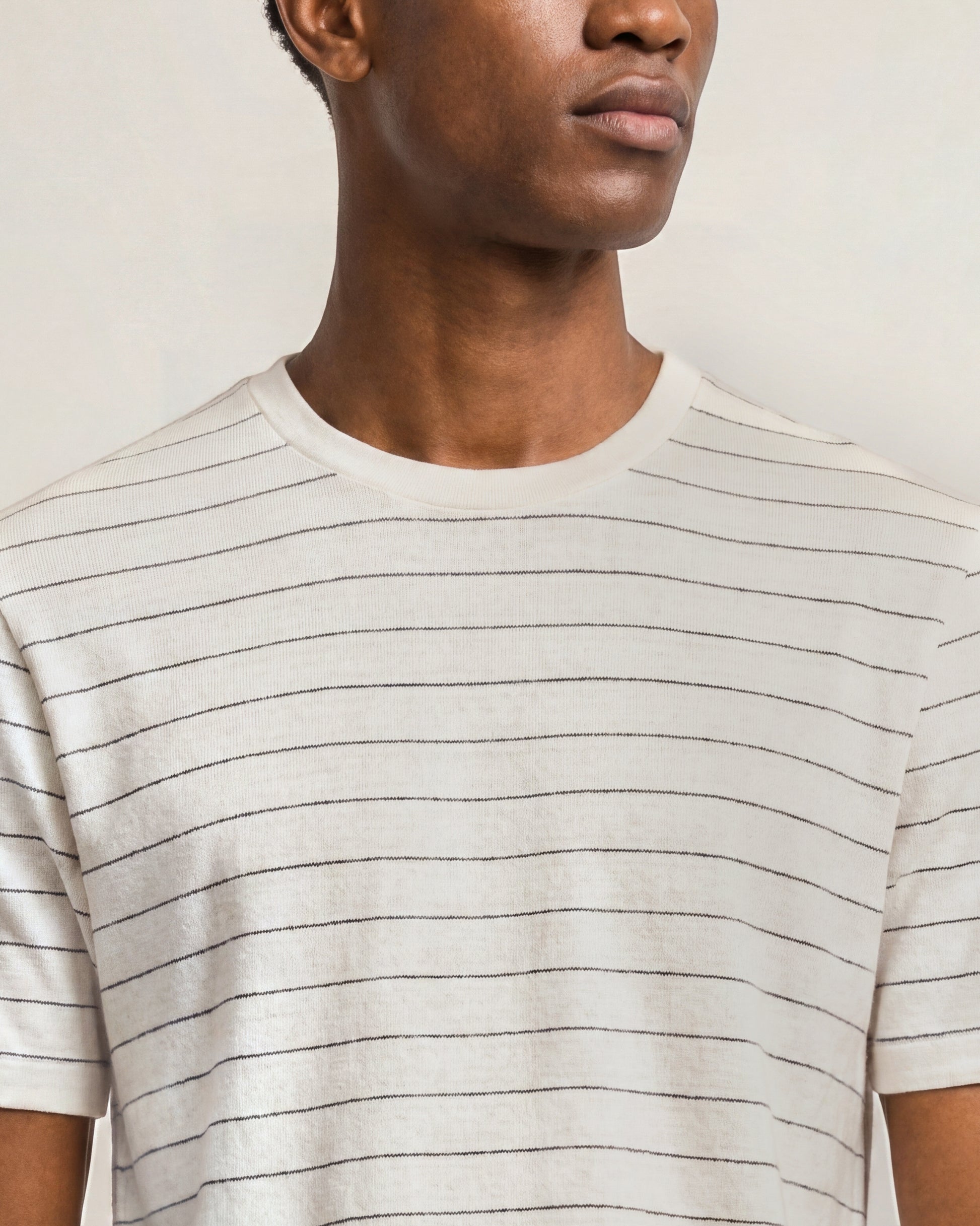 Person wearing a beige striped t-shirt against a neutral background