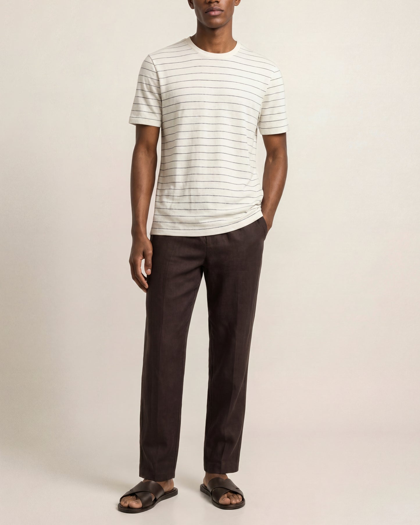 Man wearing a striped shirt and dark pants on a plain background
