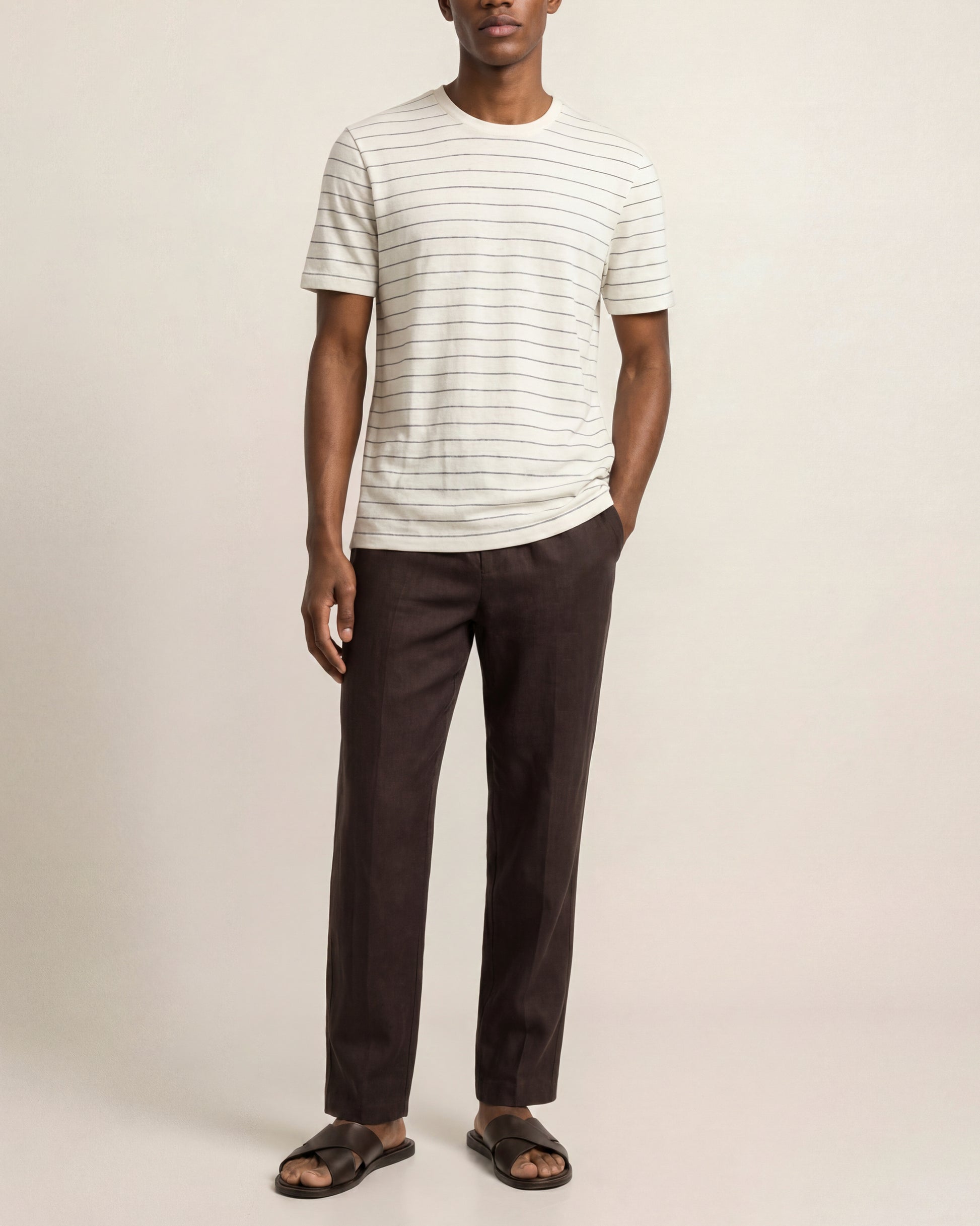 Man wearing a striped shirt and dark pants on a plain background