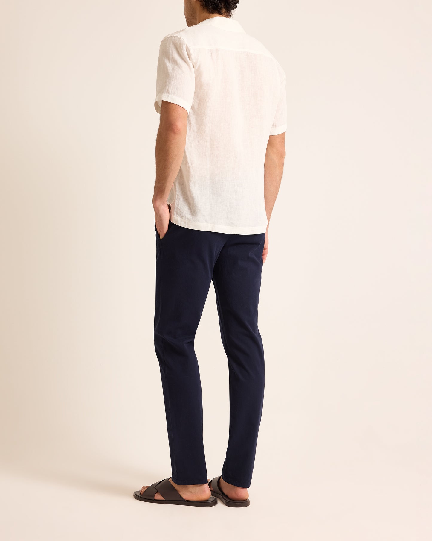 Person wearing a white shirt and navy pants on a plain background
