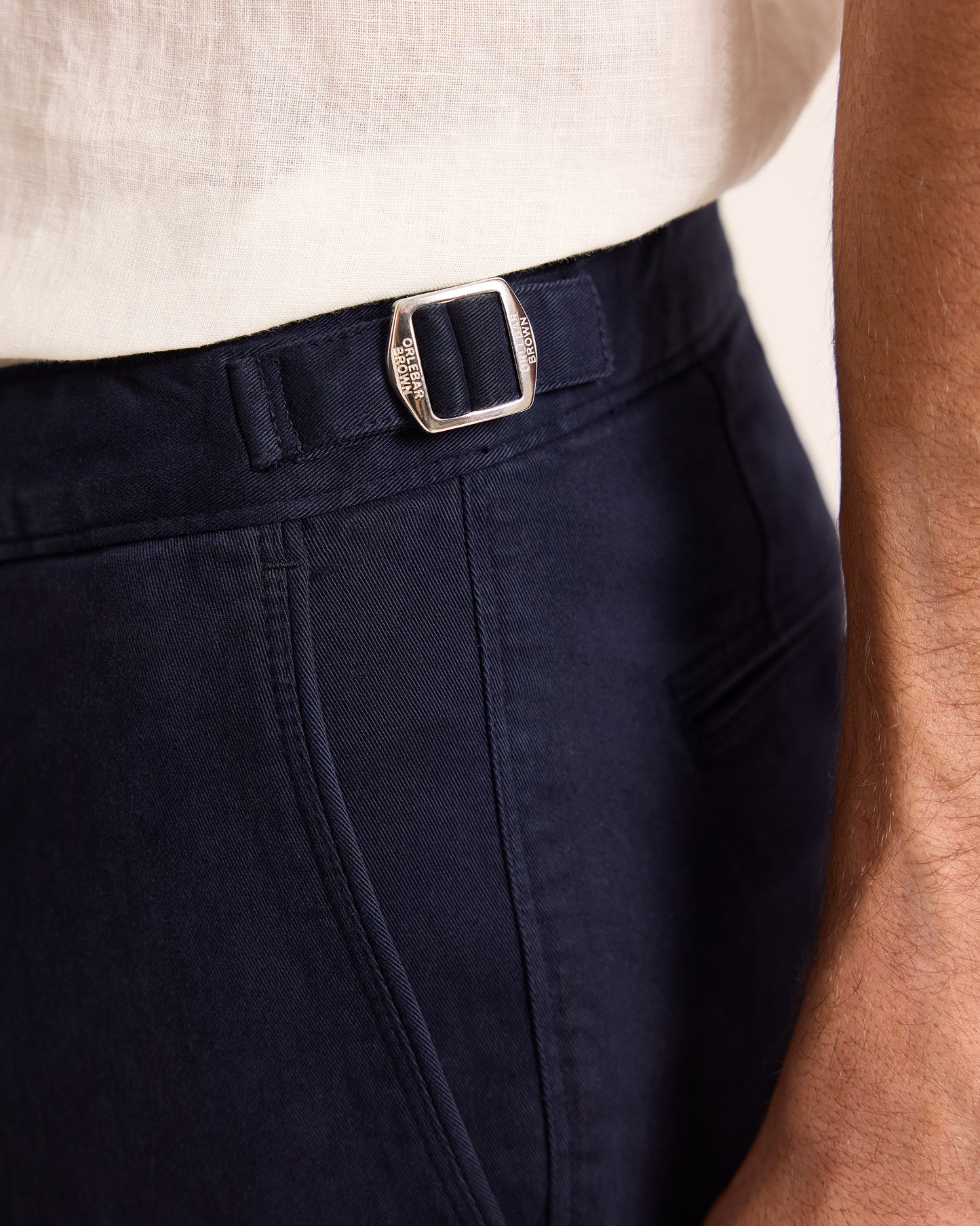 Navy pants with a silver buckle belt on a neutral background