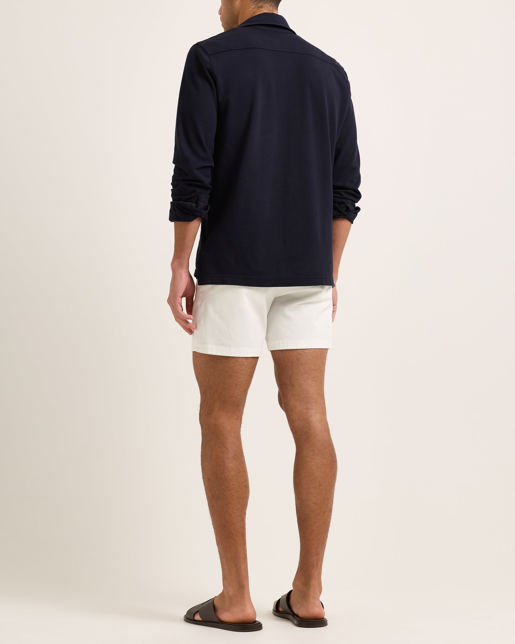 Model wearing a long sleeve navy polo shirt and white shorts on a plain background