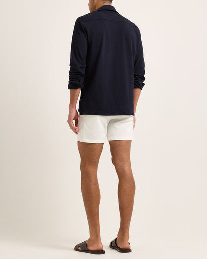 Model wearing a long sleeve navy polo shirt and white shorts on a plain background
