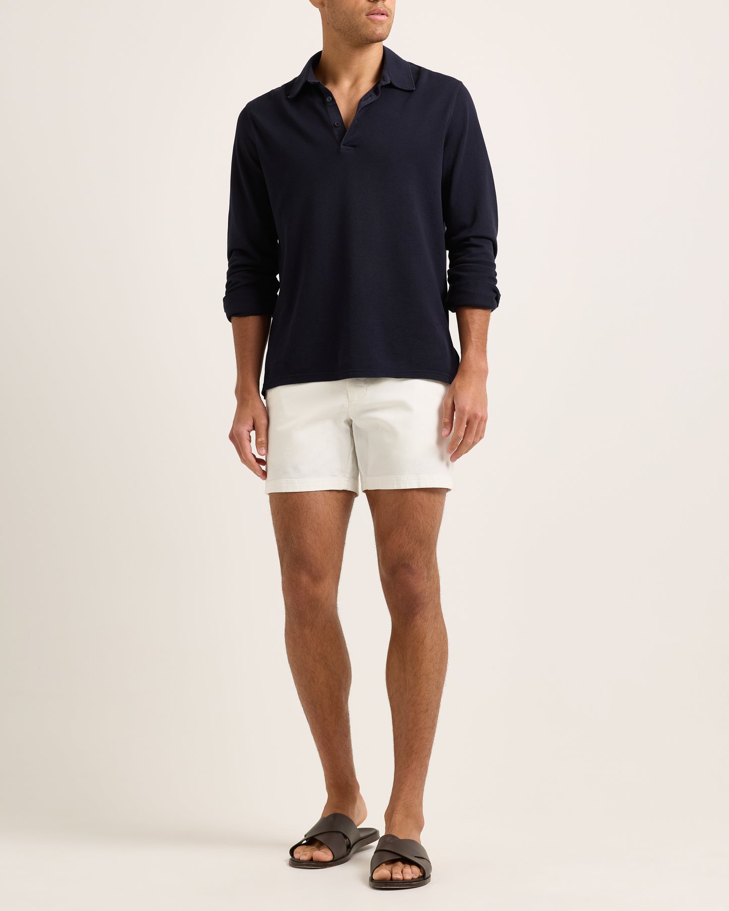 Model wearing a long sleeve navy polo shirt and white shorts on a plain background