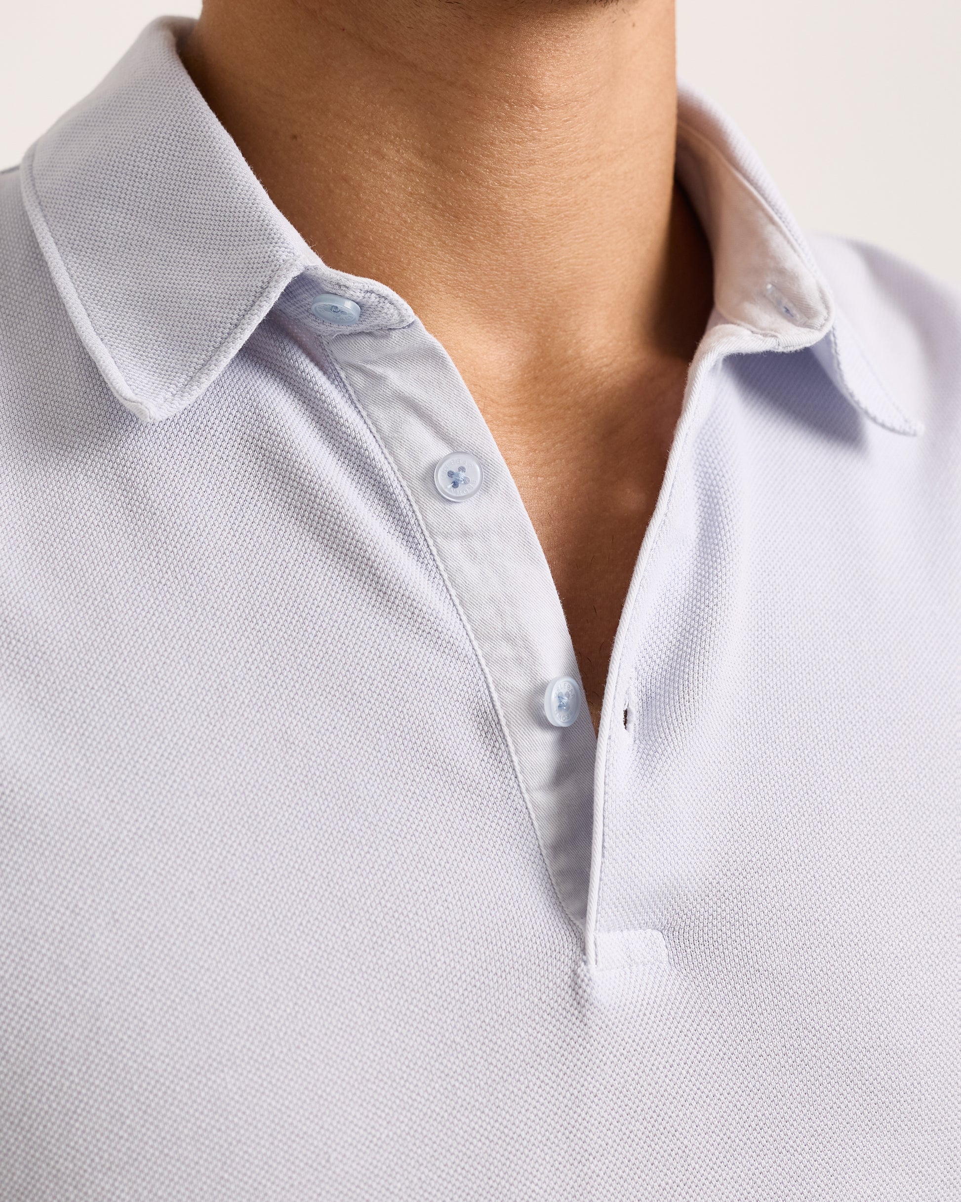 Close-up of a light blue polo shirt with collar and buttons.