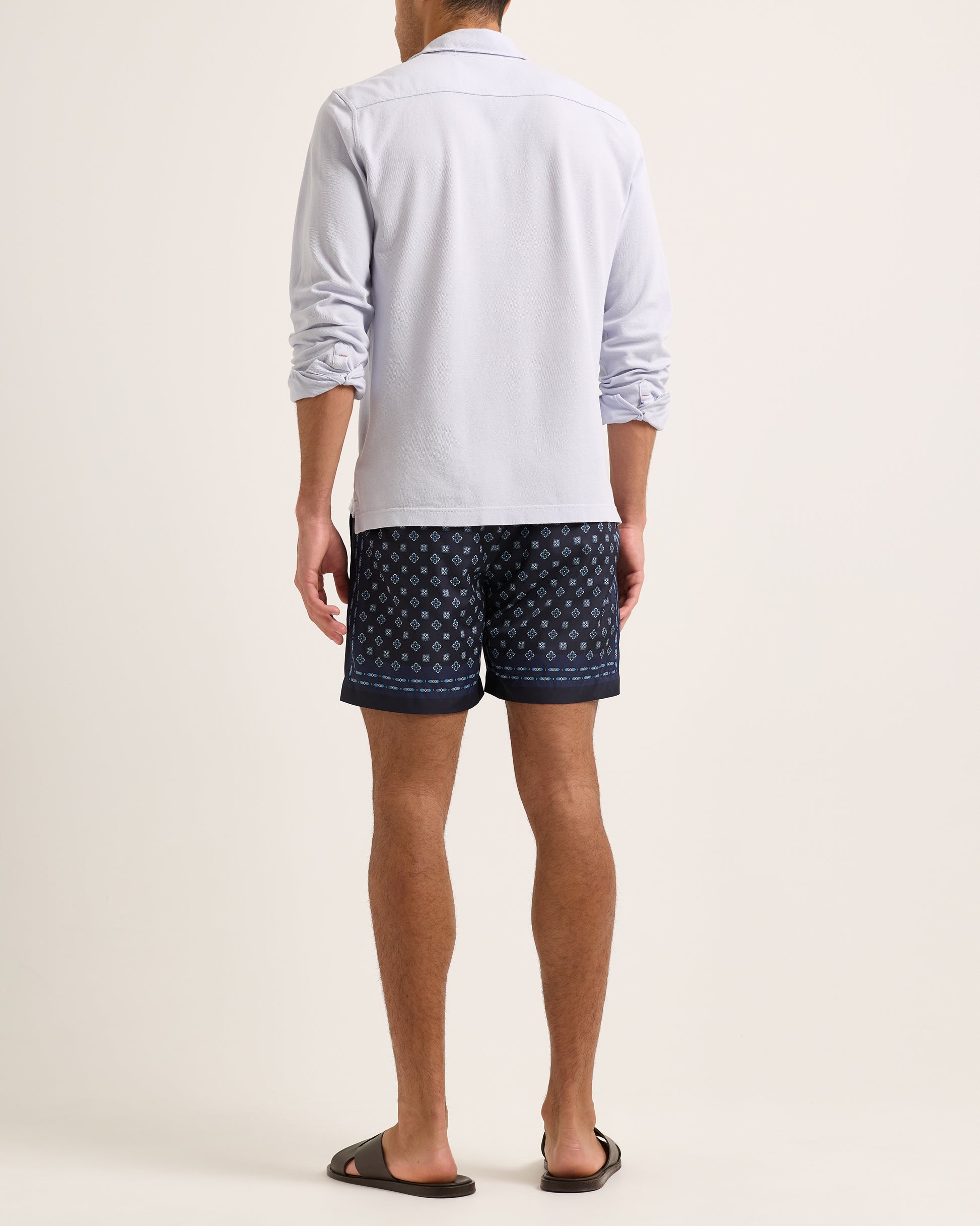 Model wearing light blue long sleeve polo shirt with swim shorts on a plain background