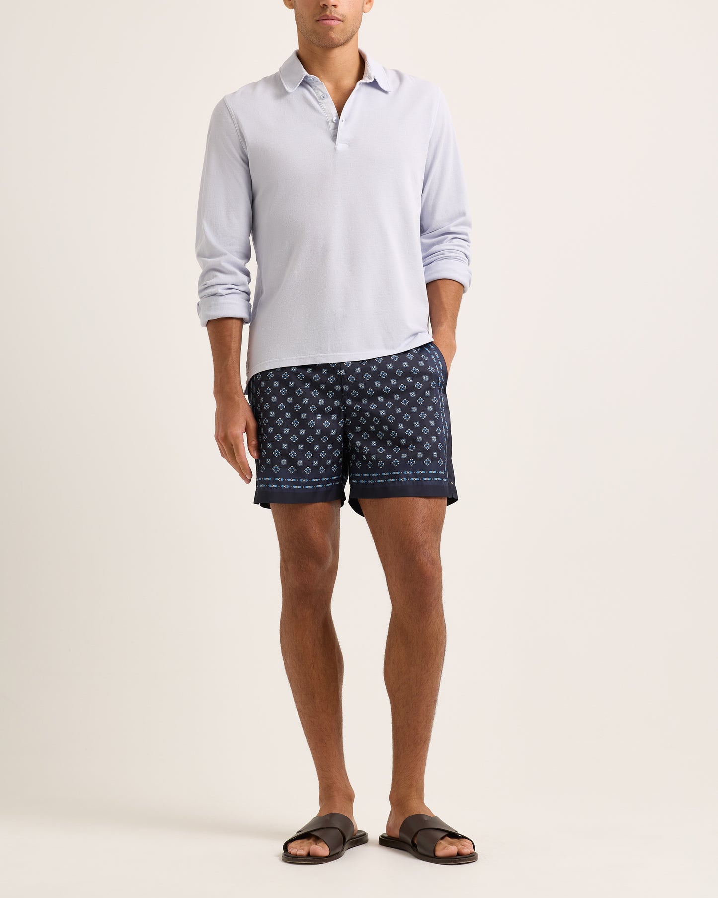 Model wearing light blue long sleeve polo shirt with swim shorts on a plain background