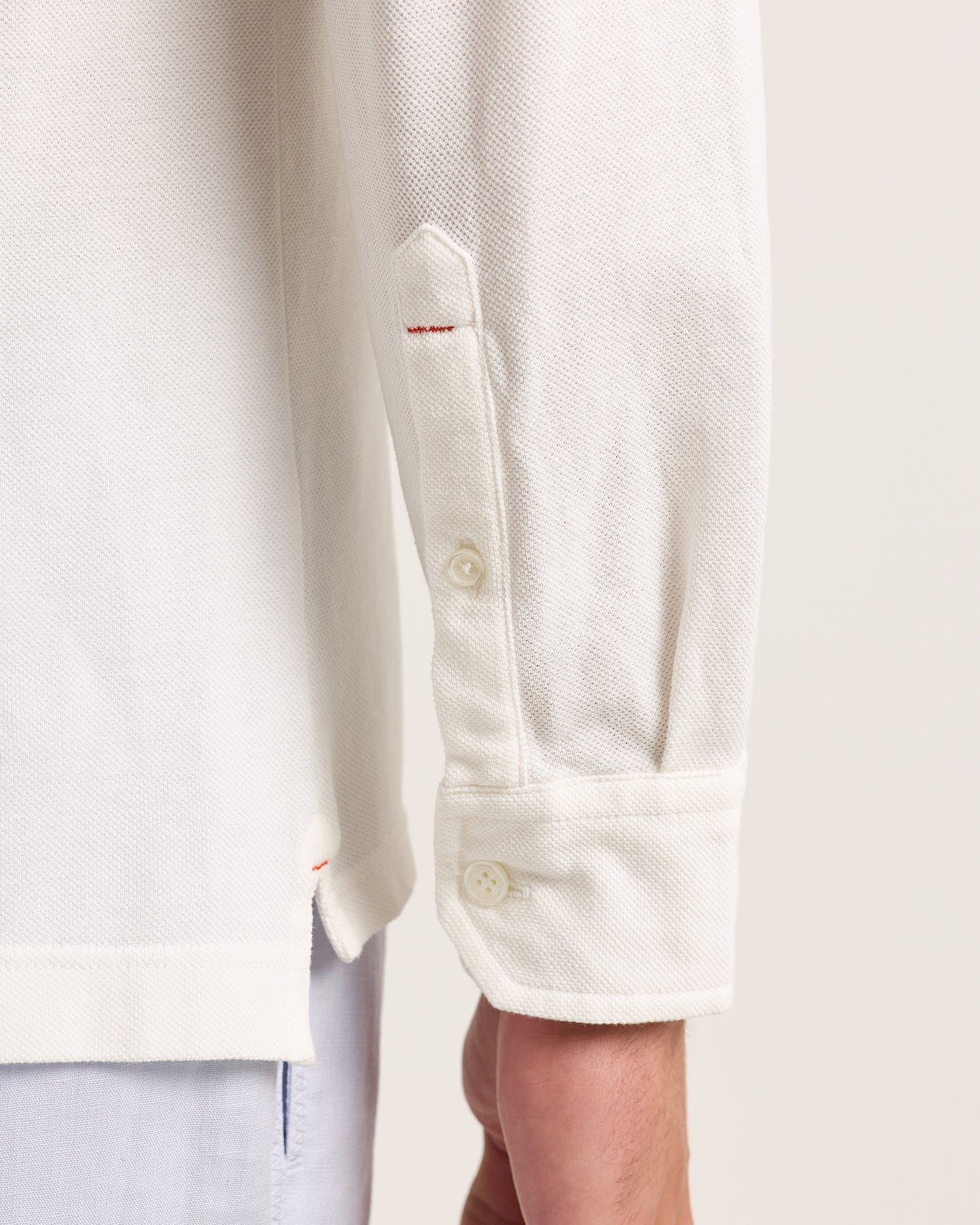 Close-up of a white polo shirt with a brand logo on a light background