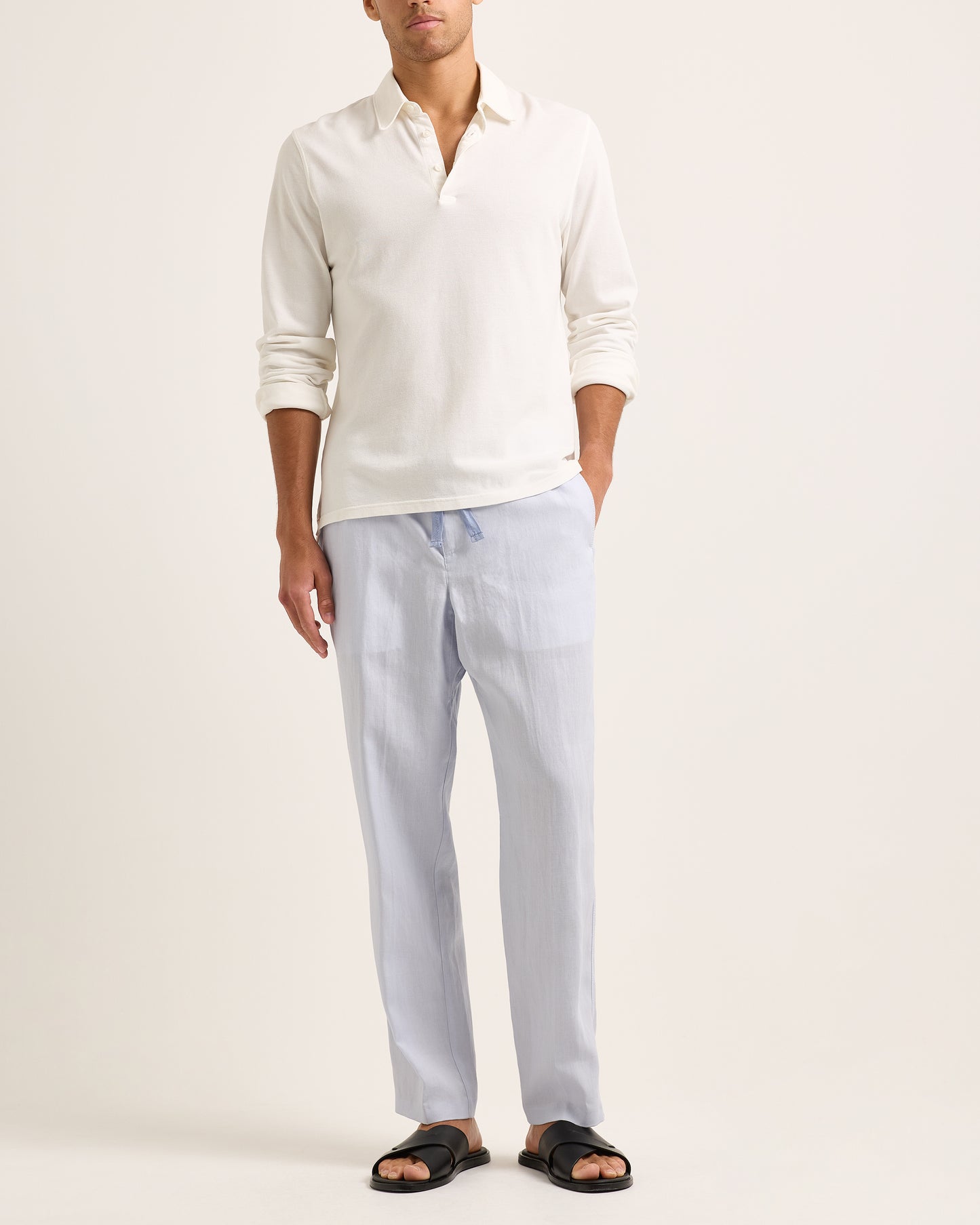 Model wearing white long-sleeve polo shirt with blue trousers on a white background