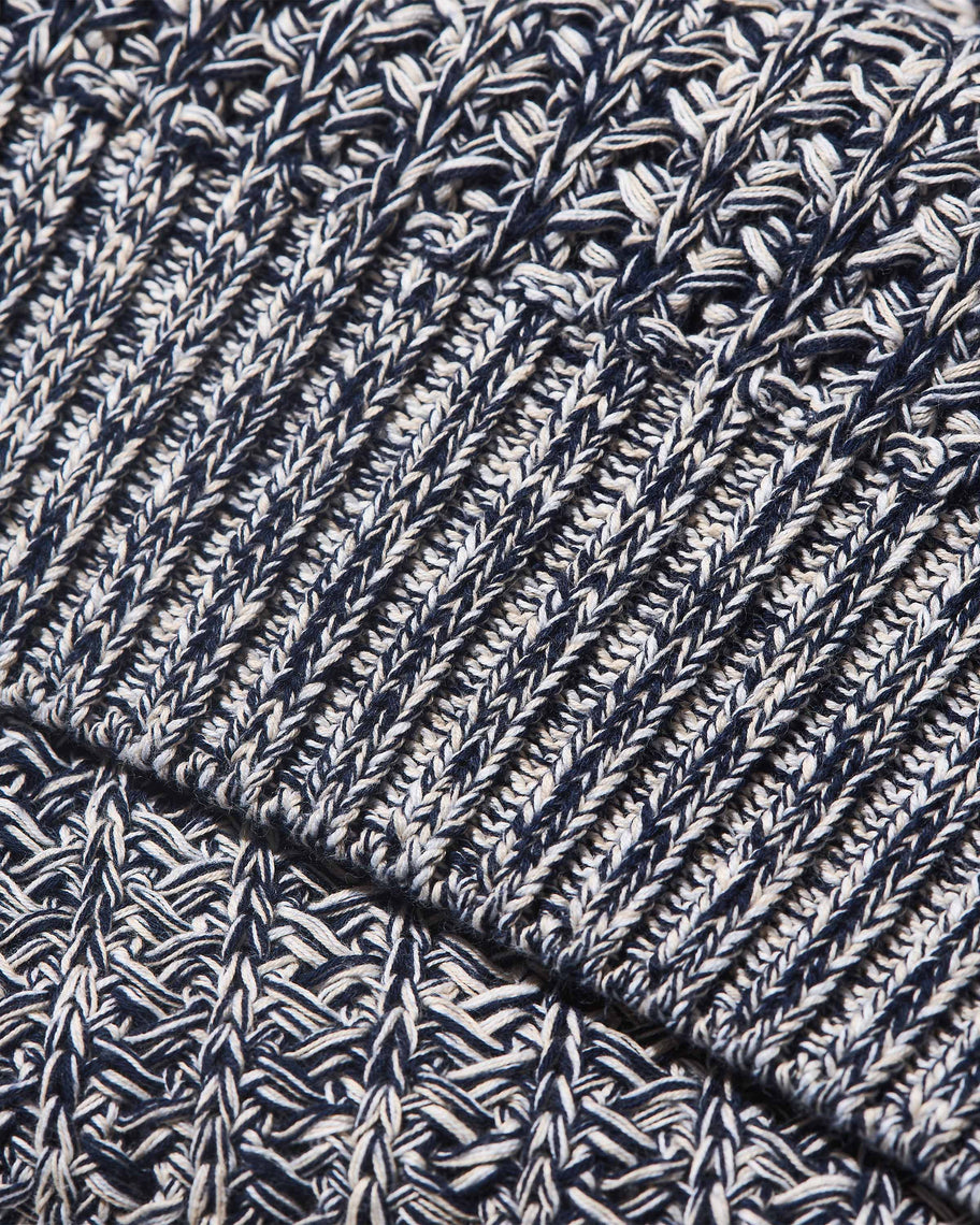 Close-up of a navy and off-white heathered knit fabric with ribbed and textured stitch patterns.