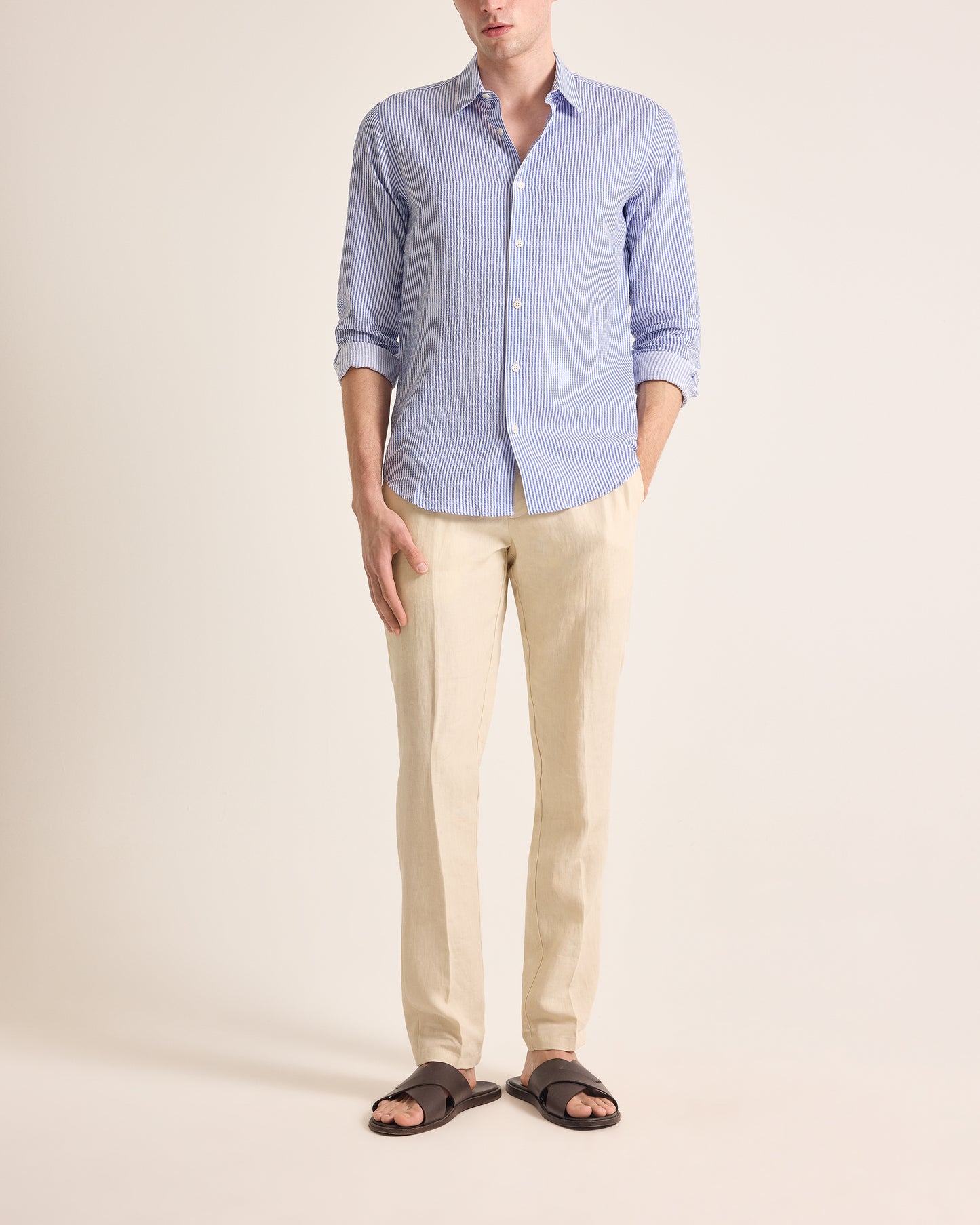 Person wearing a light blue button-up shirt and beige pants on a plain background