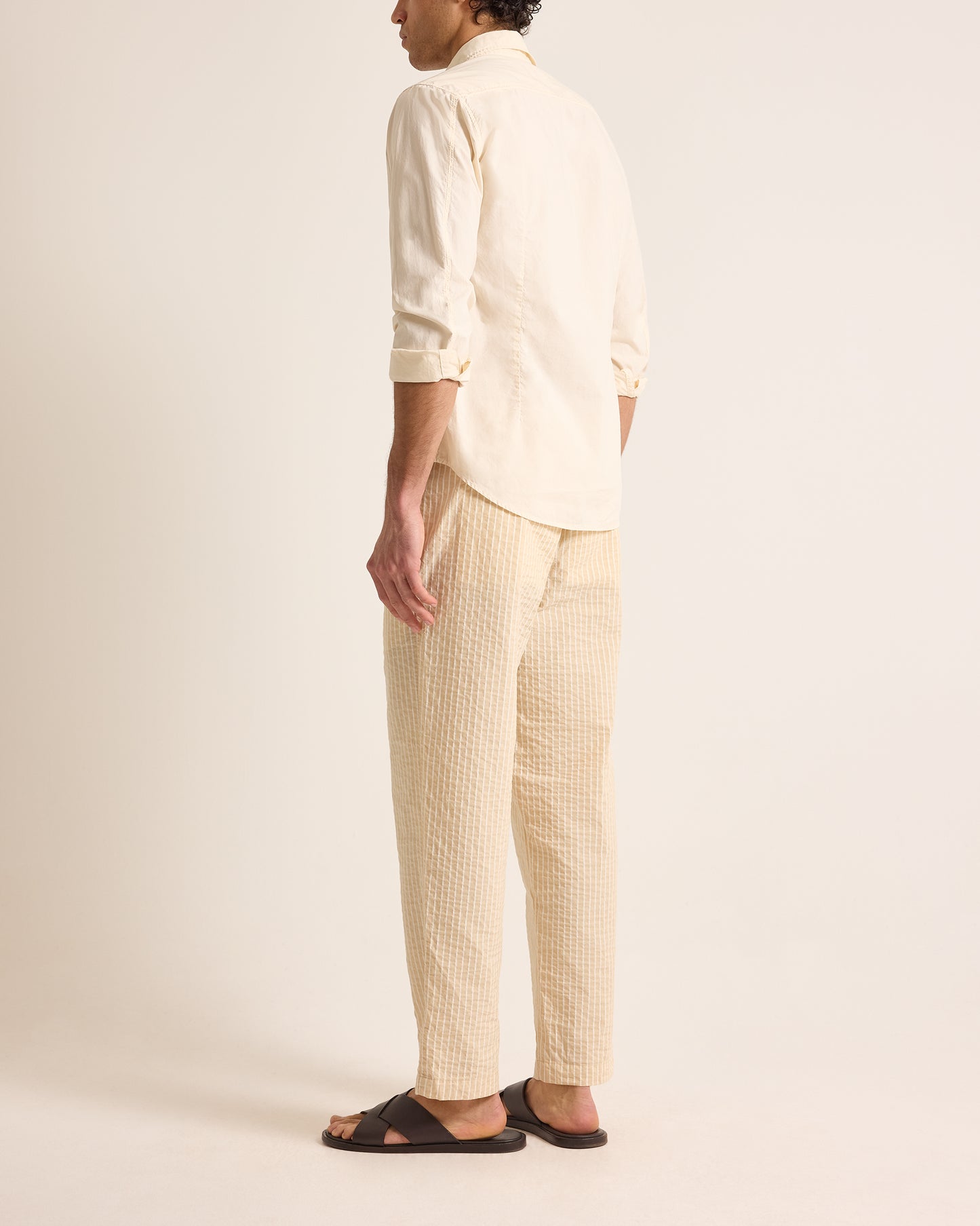 Person wearing a light-colored shirt and pants on a plain background