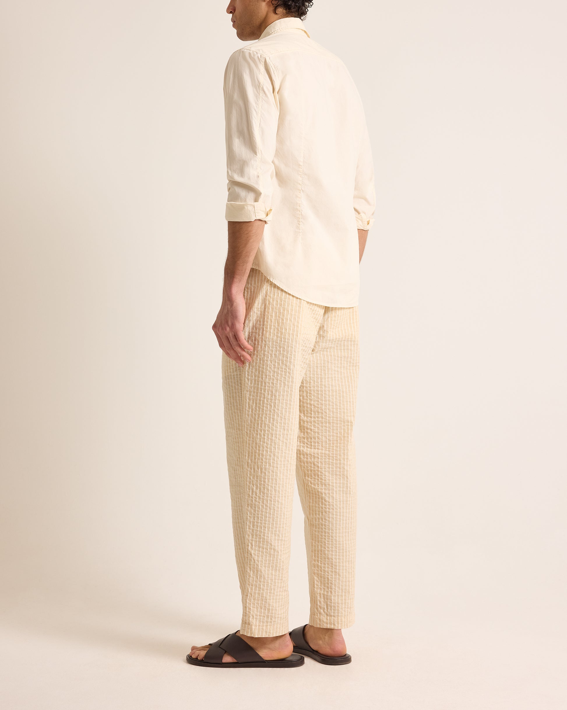 Person wearing a light-colored shirt and pants on a plain background