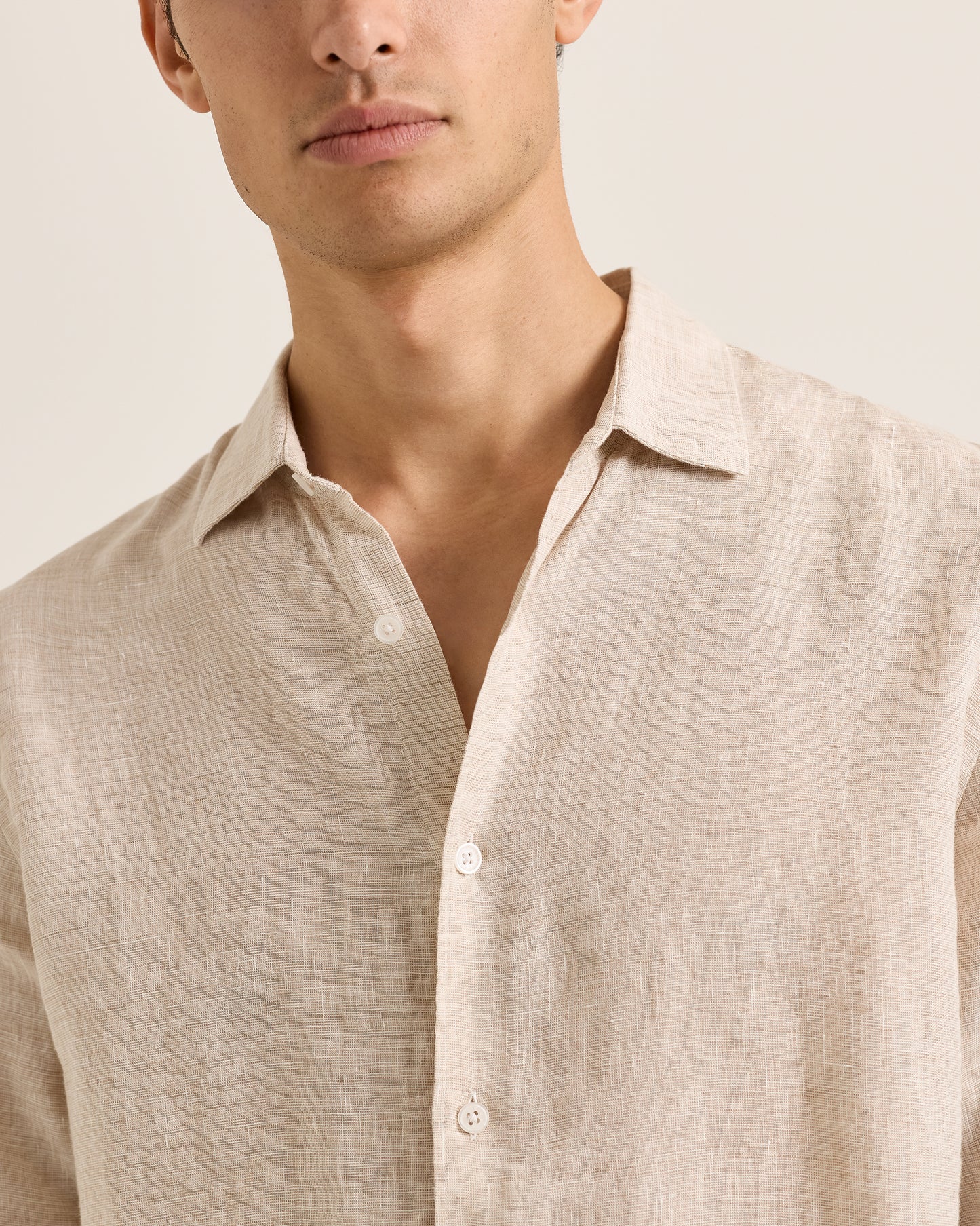 Man wearing a beige linen shirt against a neutral background