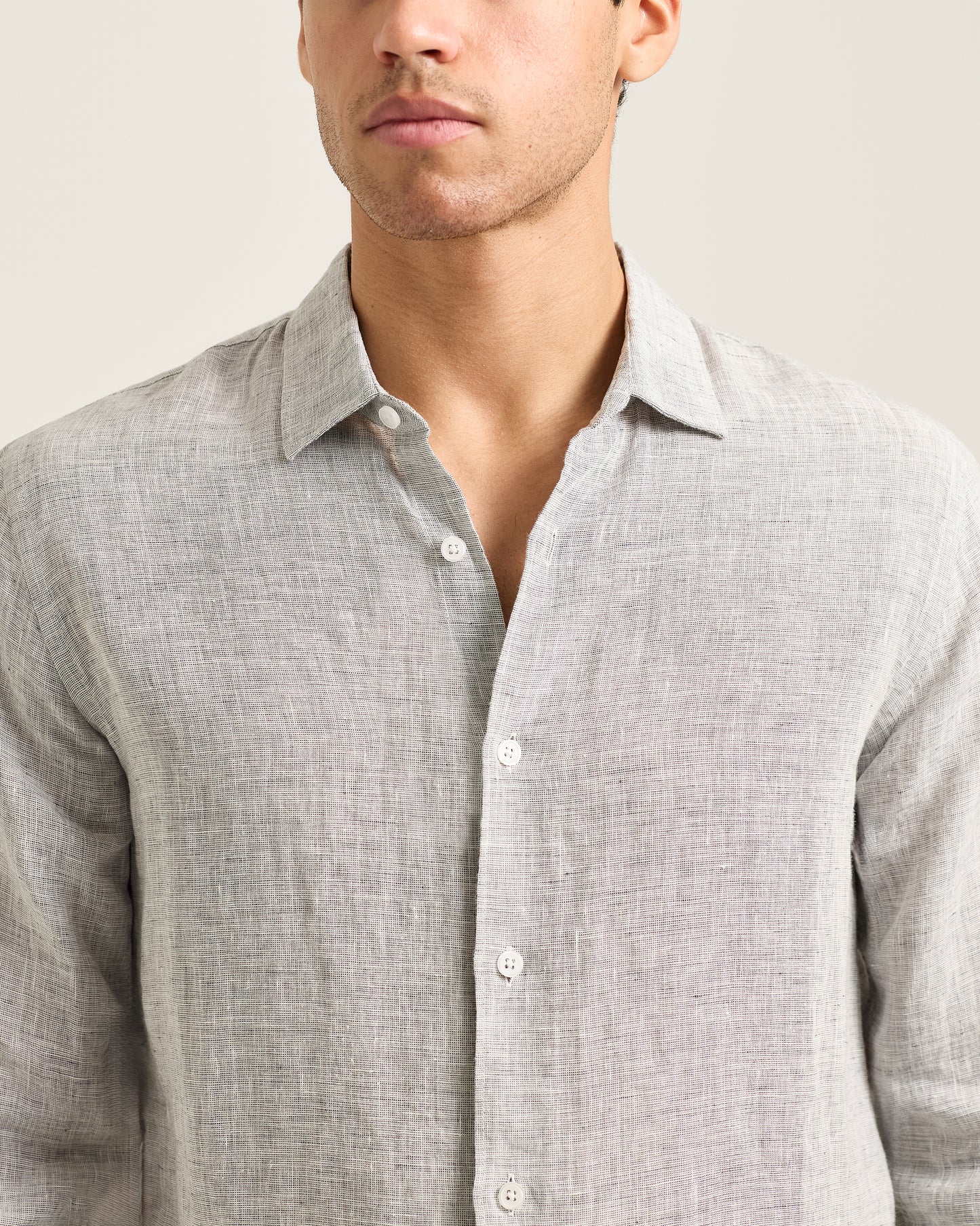 Man wearing a light gray button-up shirt against a neutral background