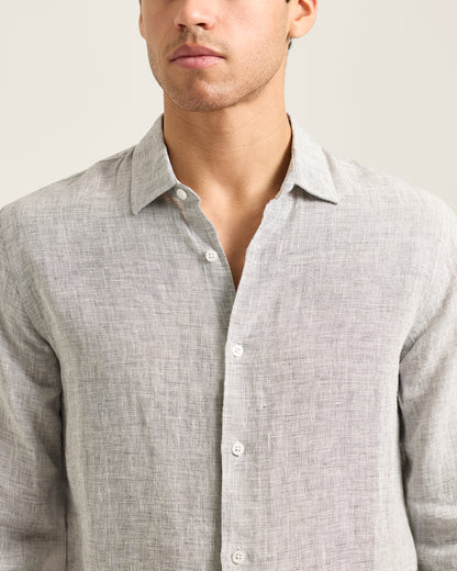 Man wearing a light gray button-up shirt against a neutral background