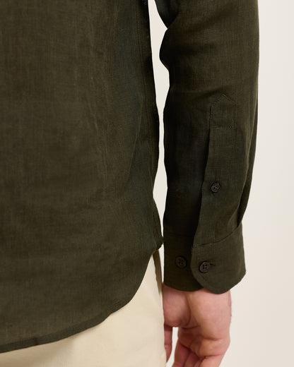 Dark green shirt with rolled-up sleeves on a neutral background