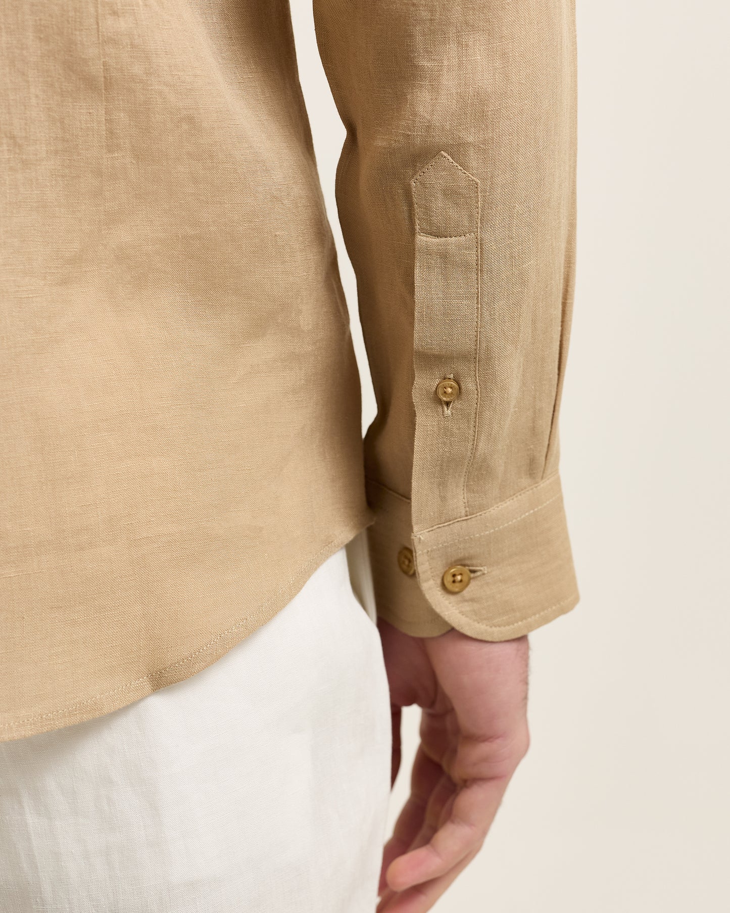 Close-up of a beige linen shirt with buttons on a white background