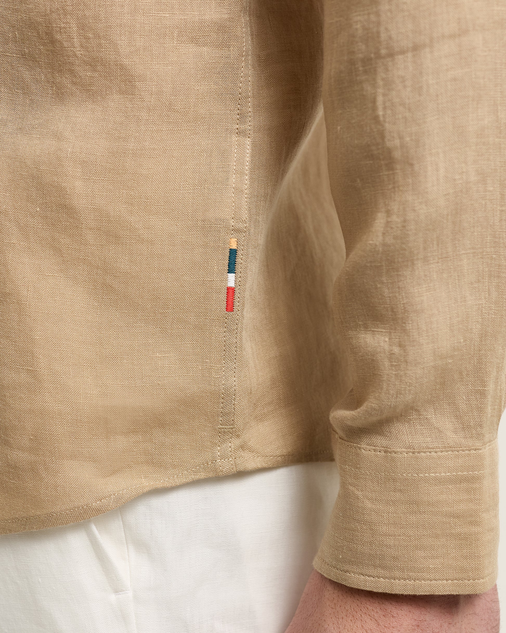 Close-up of a beige shirt with a brand label on a white background