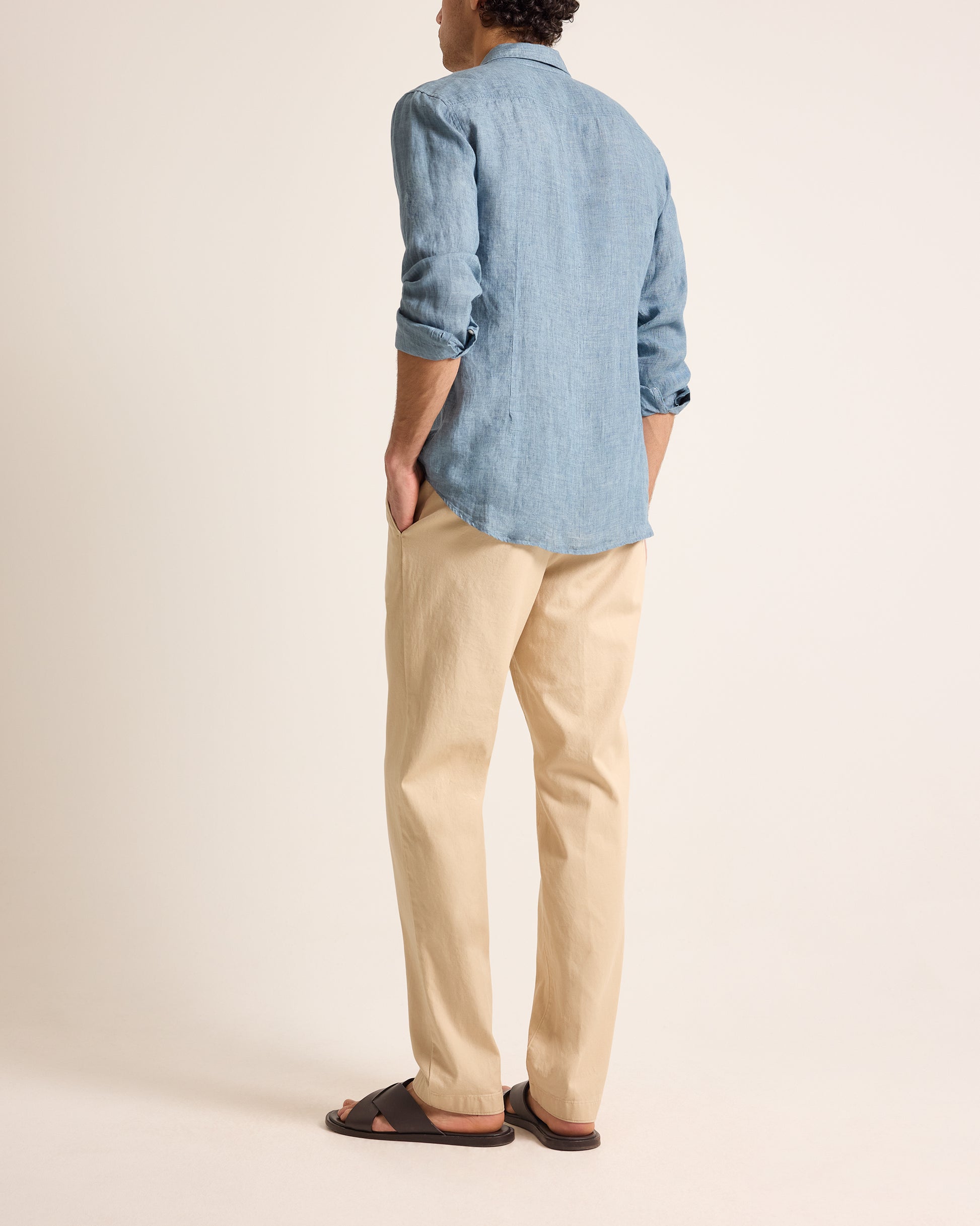 Person wearing a blue shirt and beige pants on a plain background