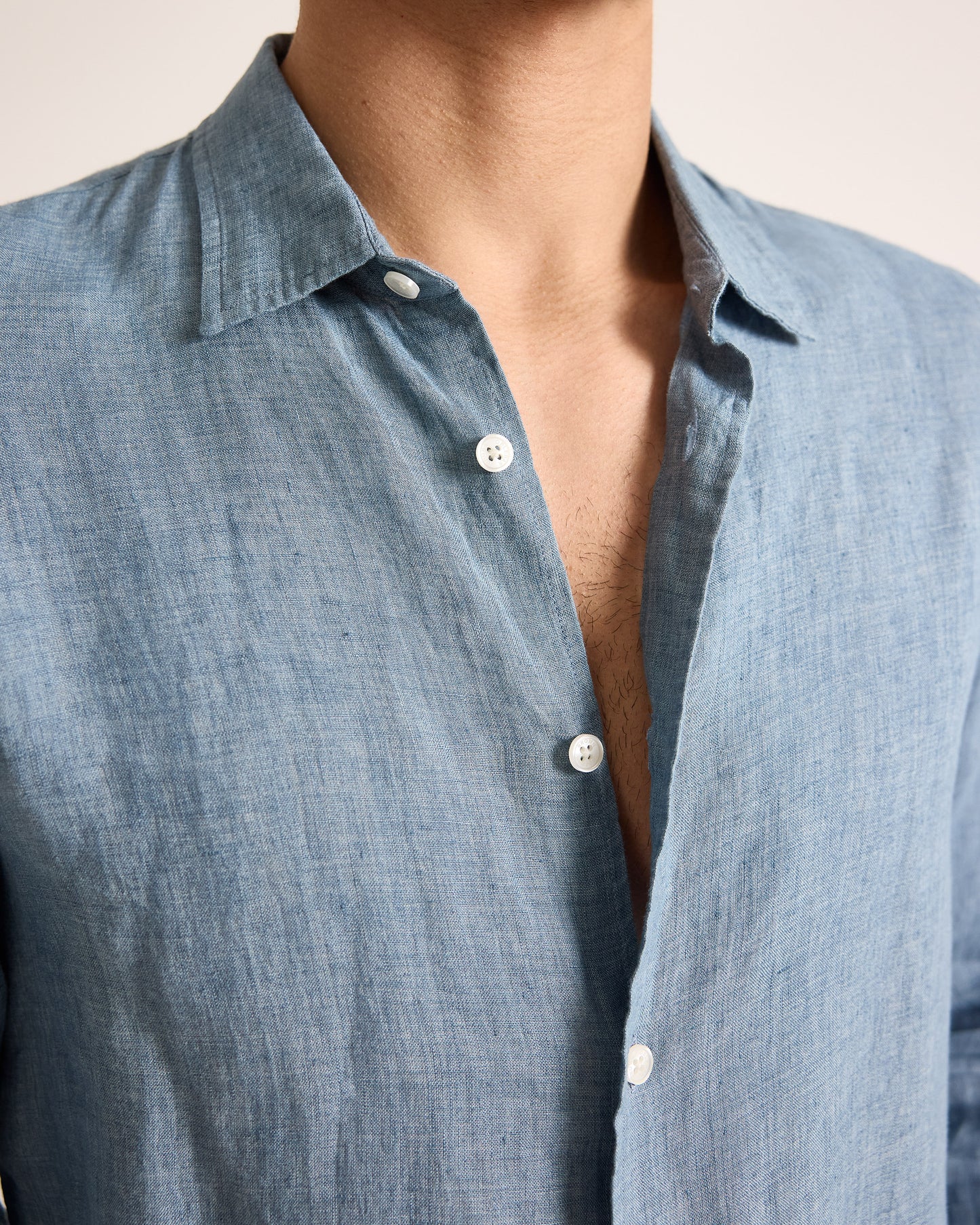 Close-up of a person wearing a light blue button-up shirt with a neutral background