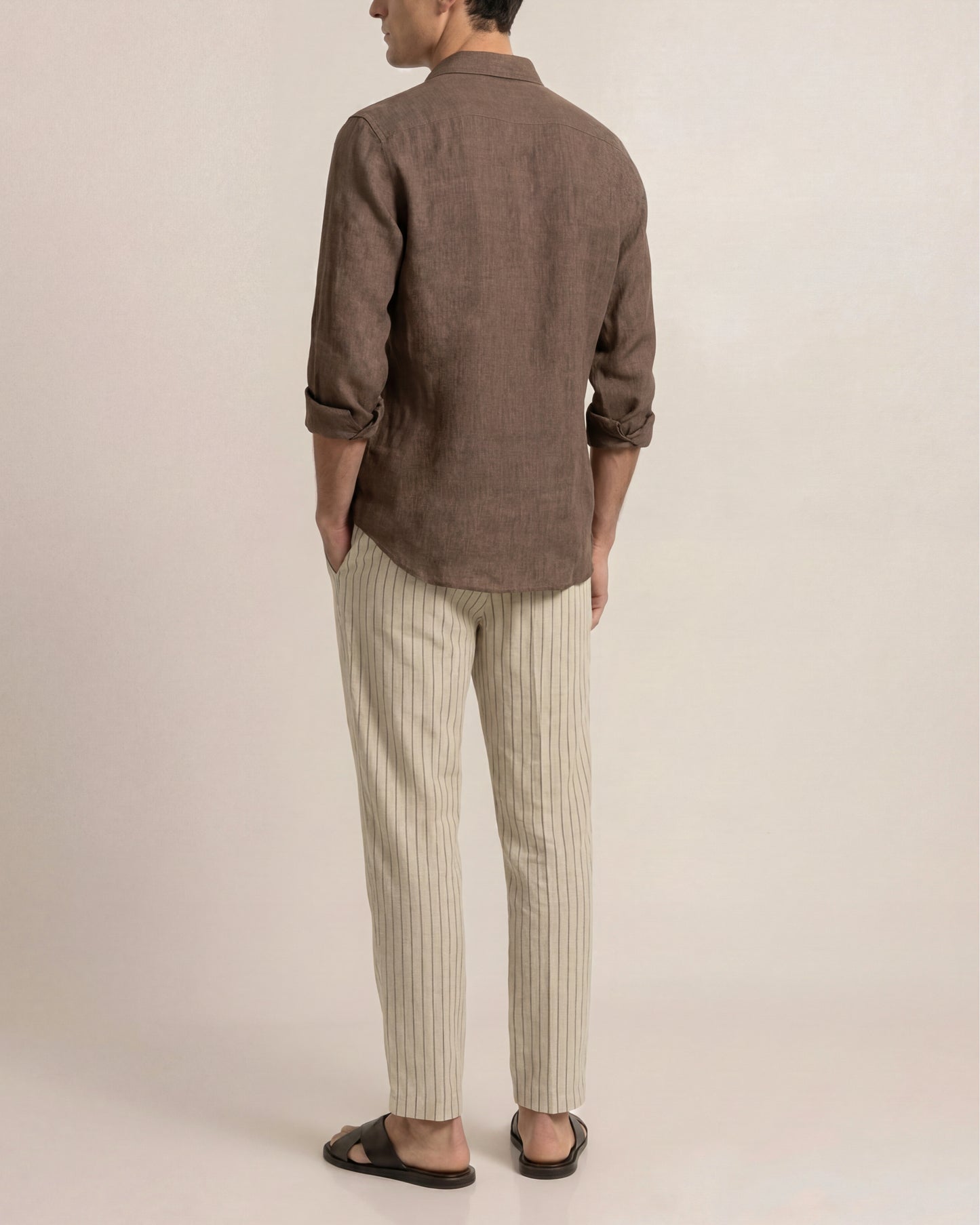 Person wearing a brown shirt and striped pants on a plain background