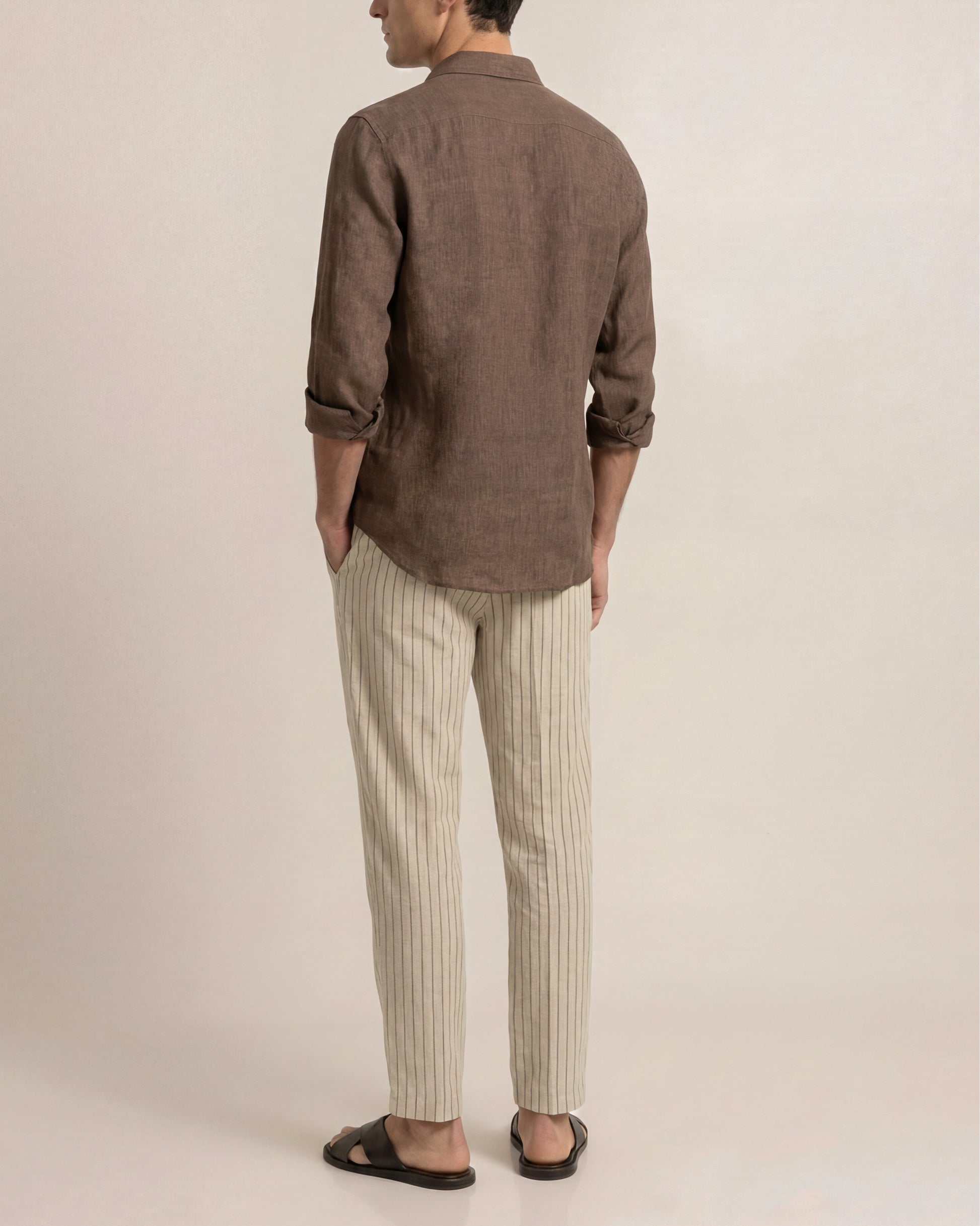 Person wearing a brown shirt and striped pants on a plain background