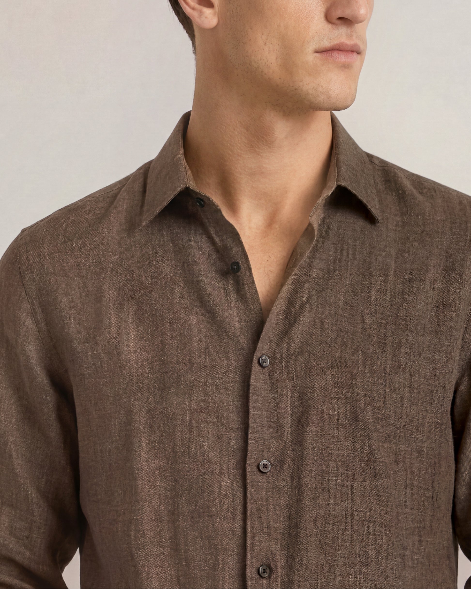 Close-up of a brown button-up shirt worn by a person on a neutral background