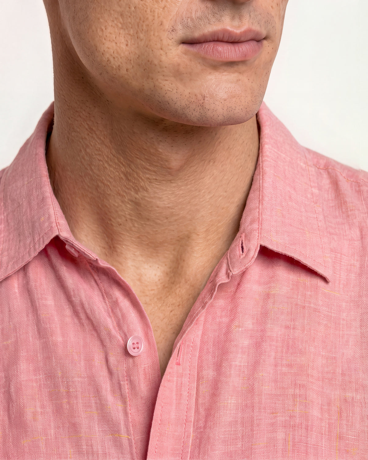 Closeup of man wearing light pink shirt on a plain background