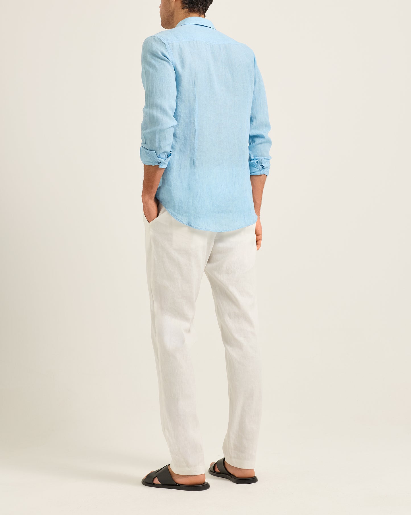 Person wearing a light blue shirt and white pants on a plain background