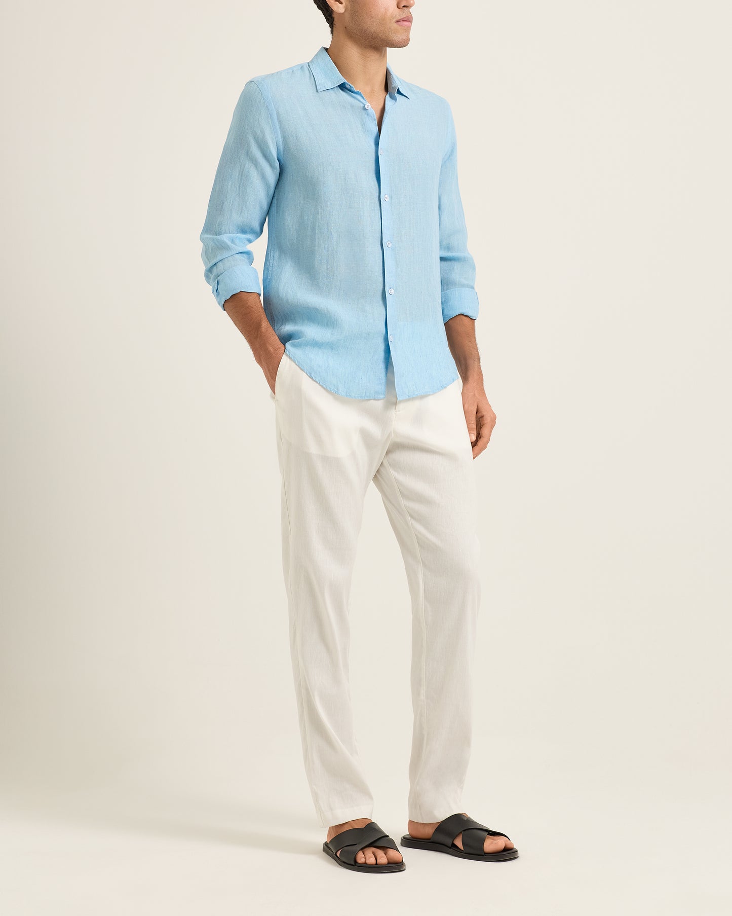Person wearing a light blue shirt and white pants on a plain background