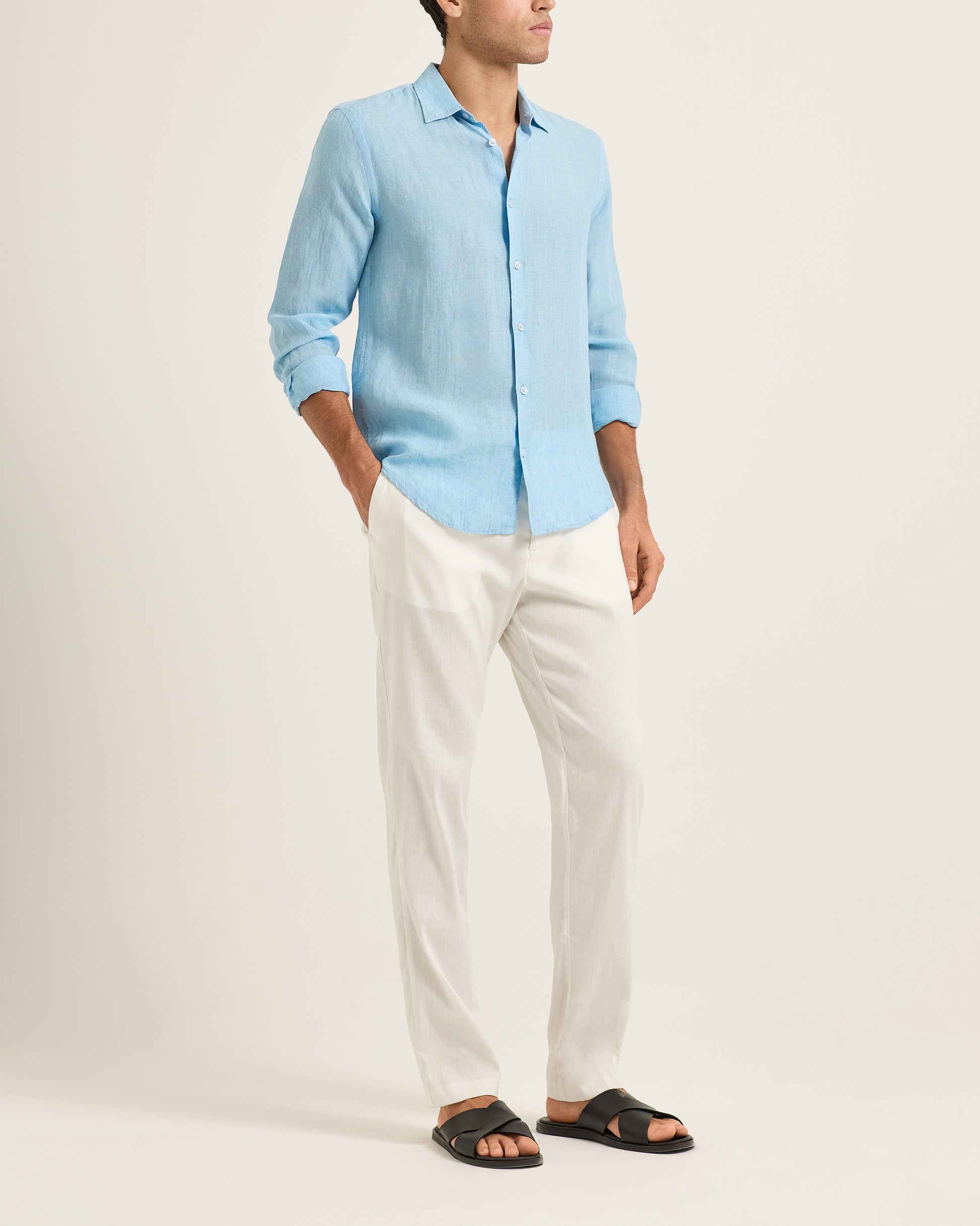Person wearing a light blue shirt and white pants on a plain background